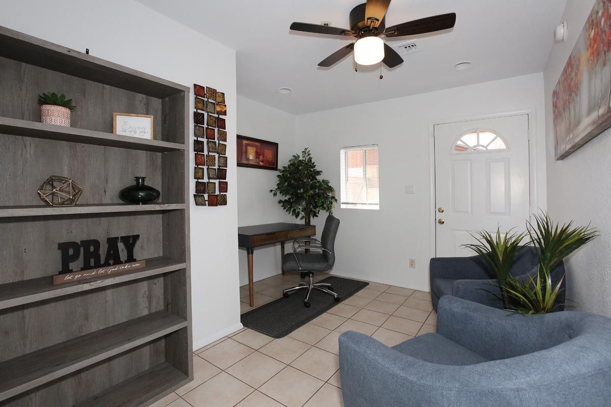 A living room with a ceiling fan and a sign that says pray