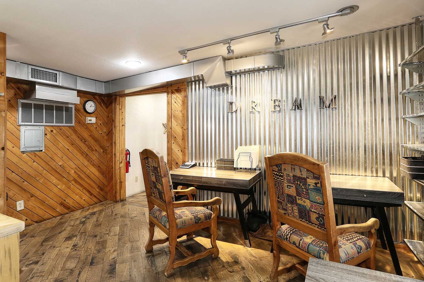 A room with a desk , chairs and a clock on the wall.