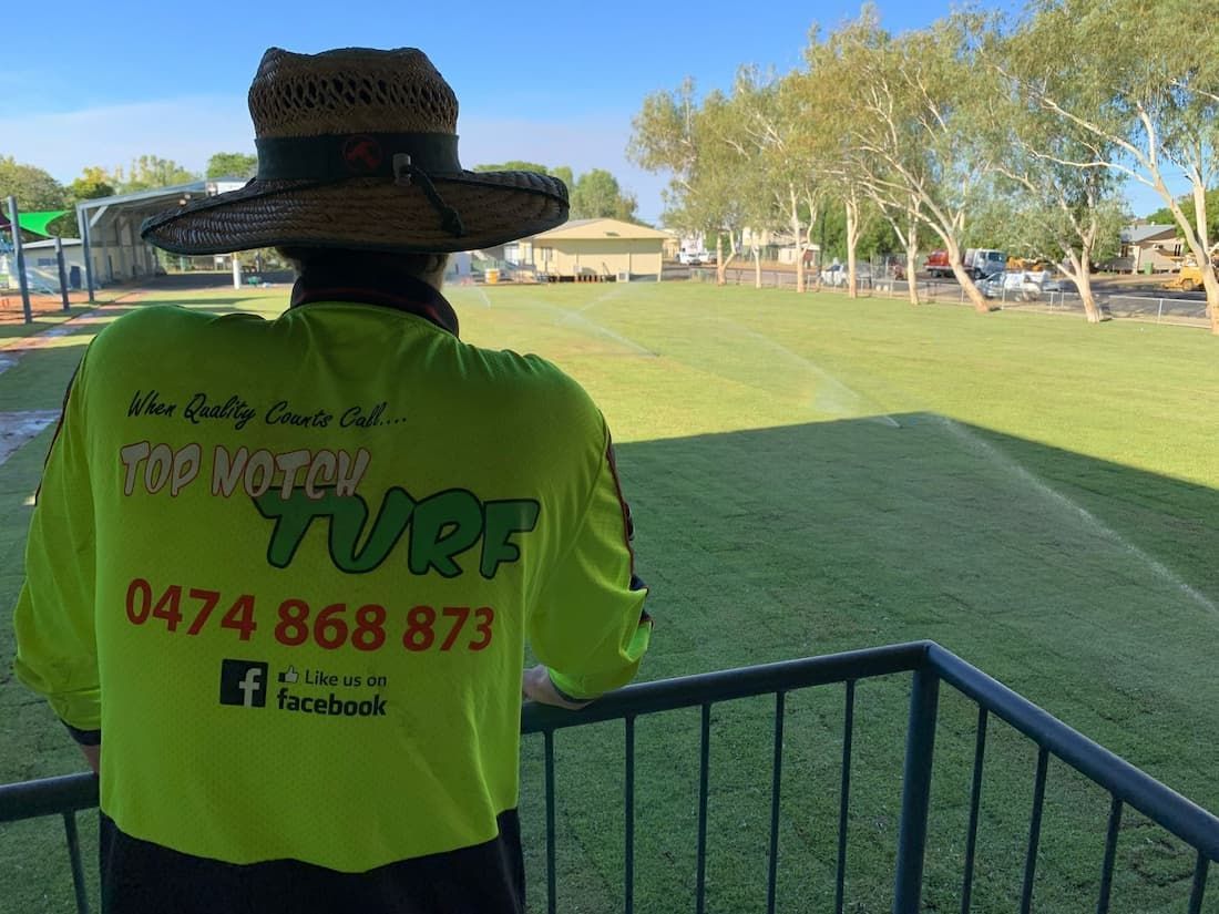 A Group of People Are Standing on Top of A Lush Green Field — Top Notch Turf in Rasmussen, QLD