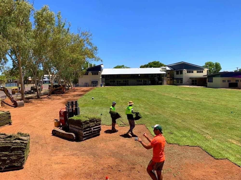 A Group of People Are Standing on Top of A Lush Green Field — Top Notch Turf in Rasmussen, QLD