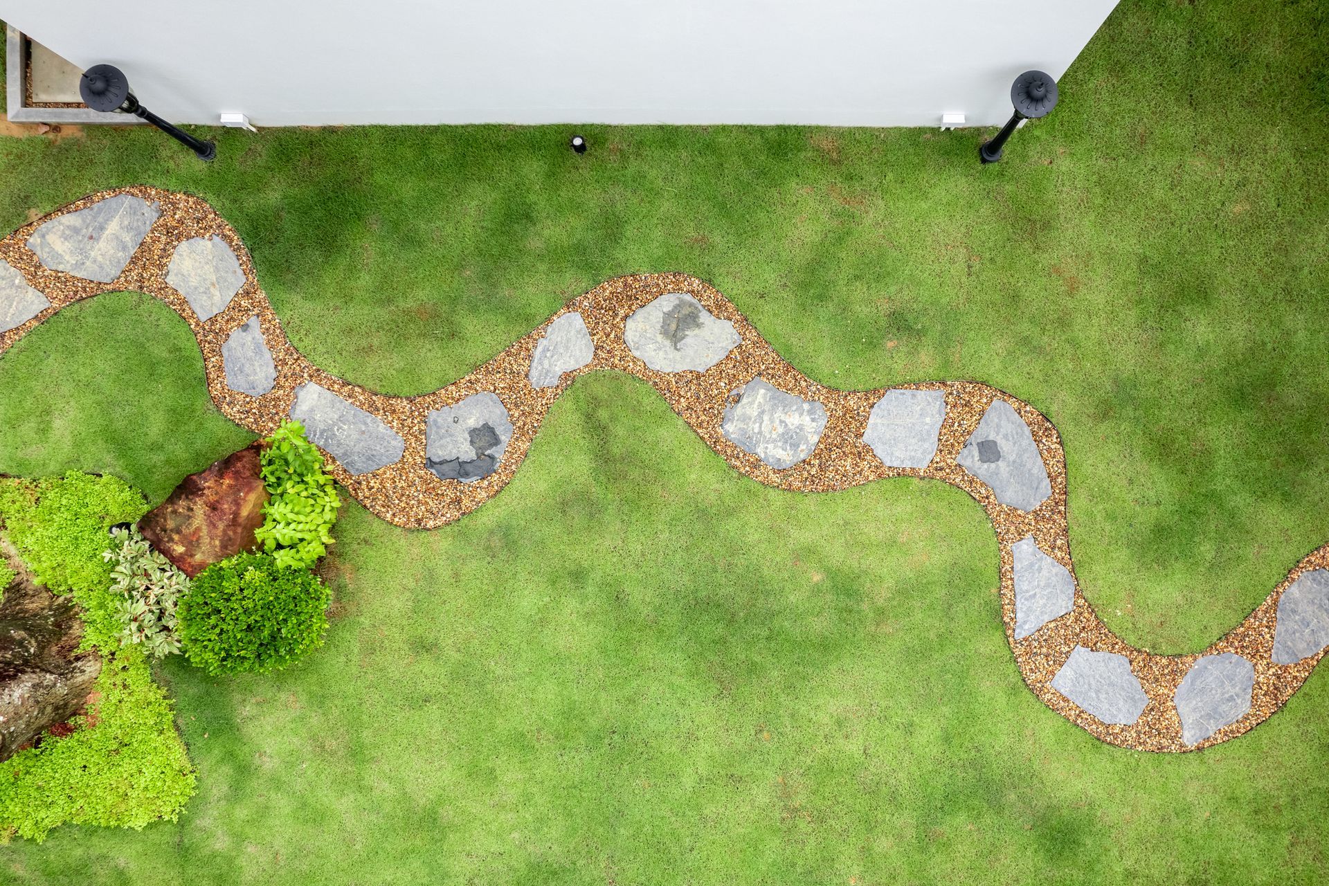 Landscaping Contractor—Curved stone pathway with mulch and green lawn, aerial view of garden design.