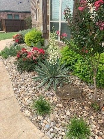 A front yard featuring a variety of colorful flowers surrounded by decorative rocks.