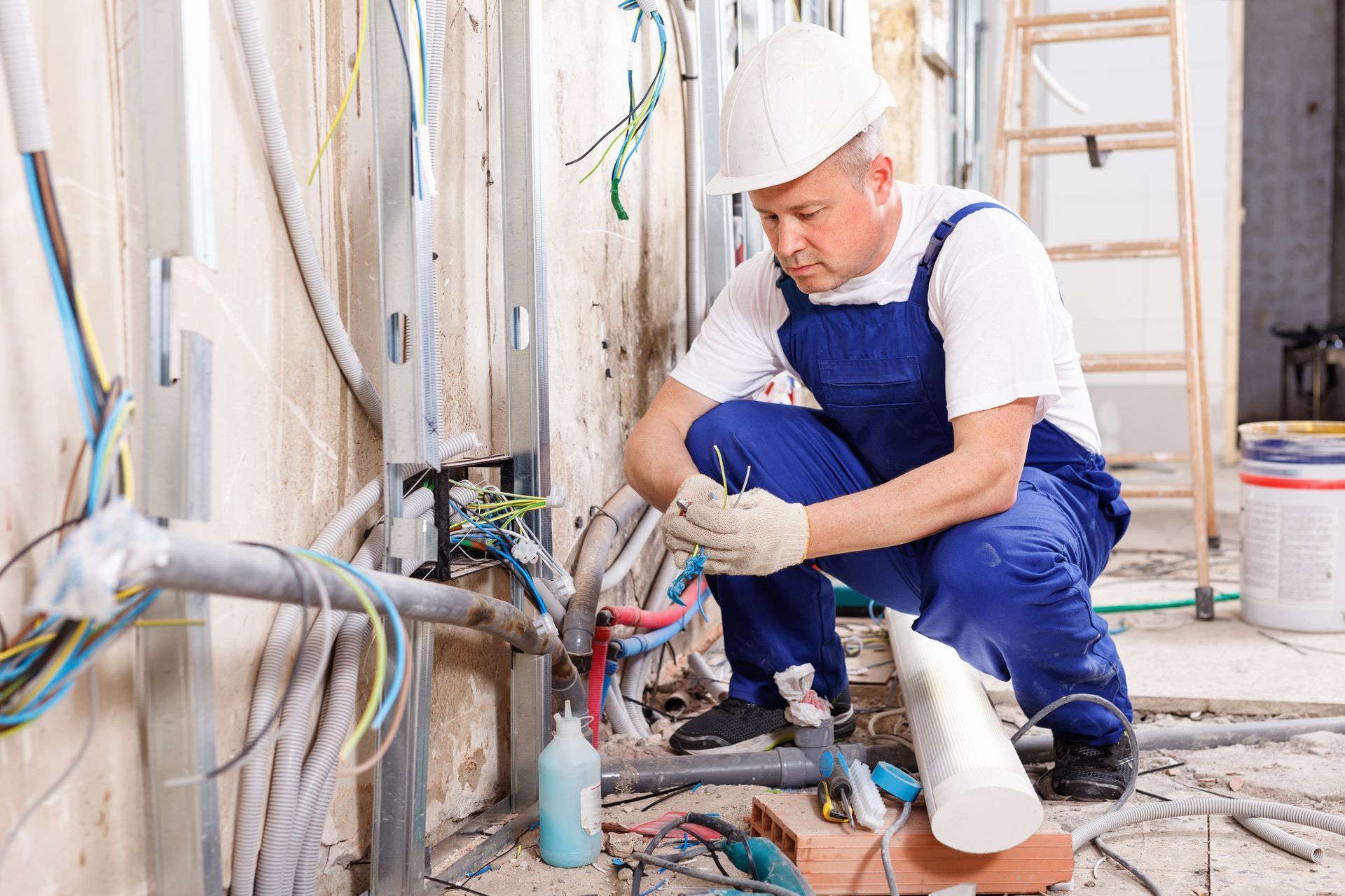 An experienced electrician laying electric wires in a building under construction. An experienced electrician laying electric wires in a building under construction.