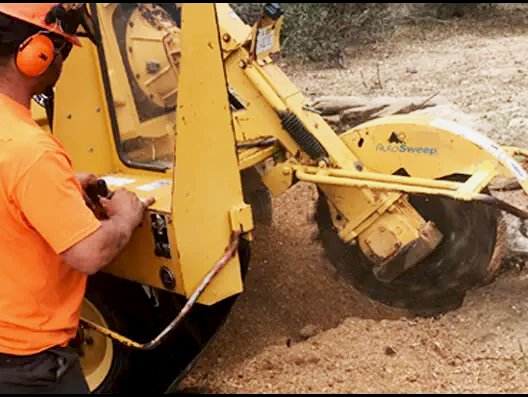 A man in an orange shirt is working on a yellow machine
