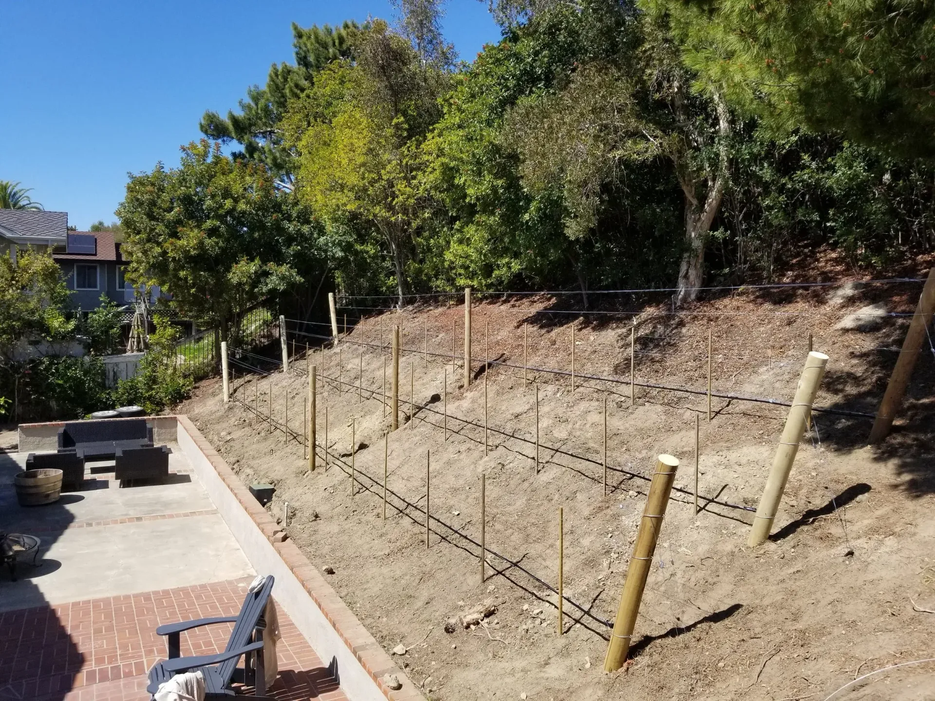 A backyard with a retaining wall and construction of a fence.