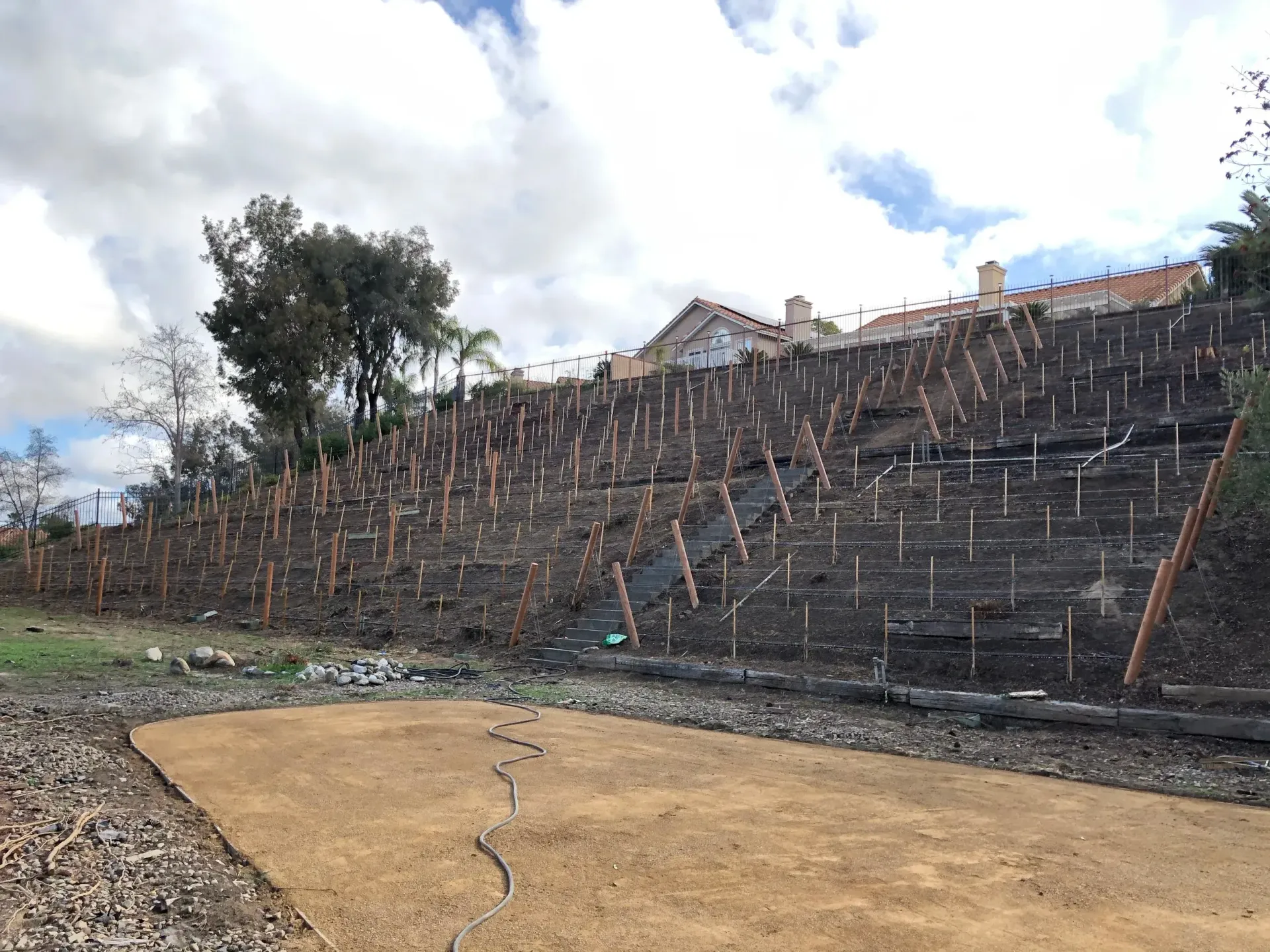 Burnt hillside with erosion control measures in place, brown and tan hues, residential setting.