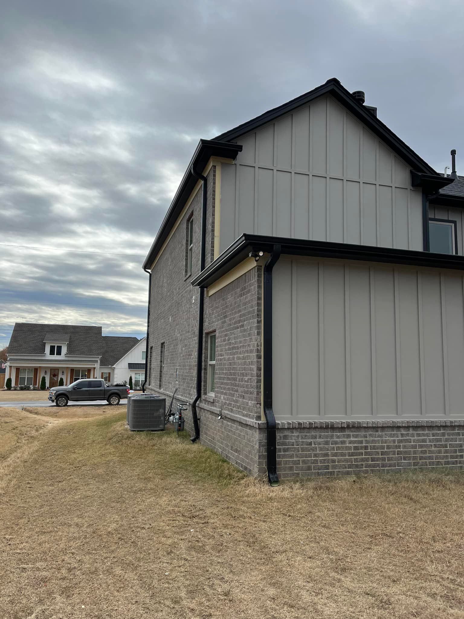 A large house with a lot of windows is sitting on top of a dirt field.