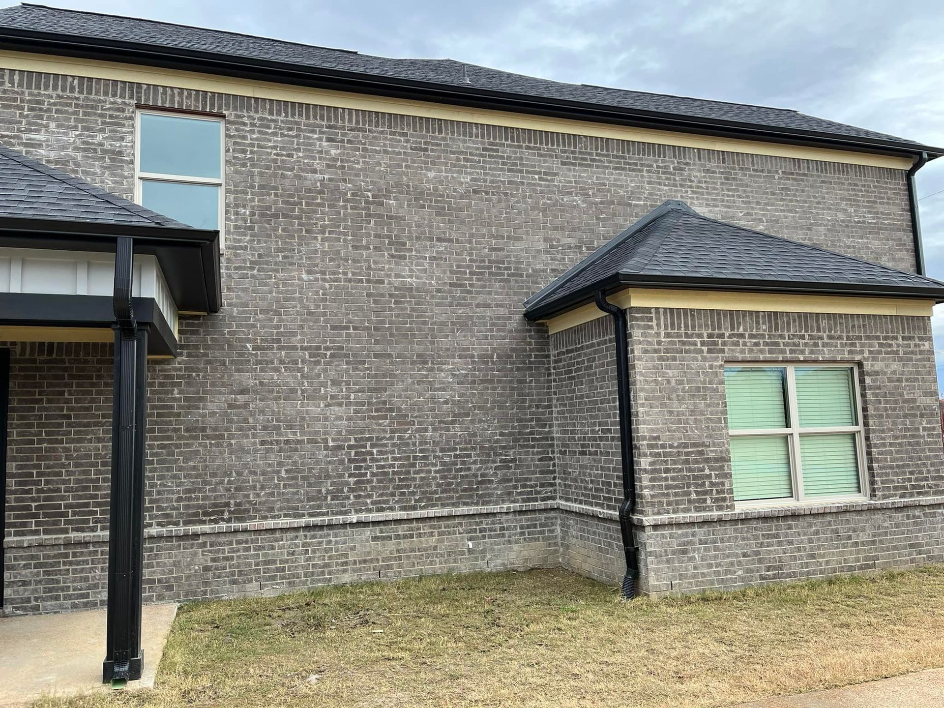 A large brick building with a black roof and a porch.