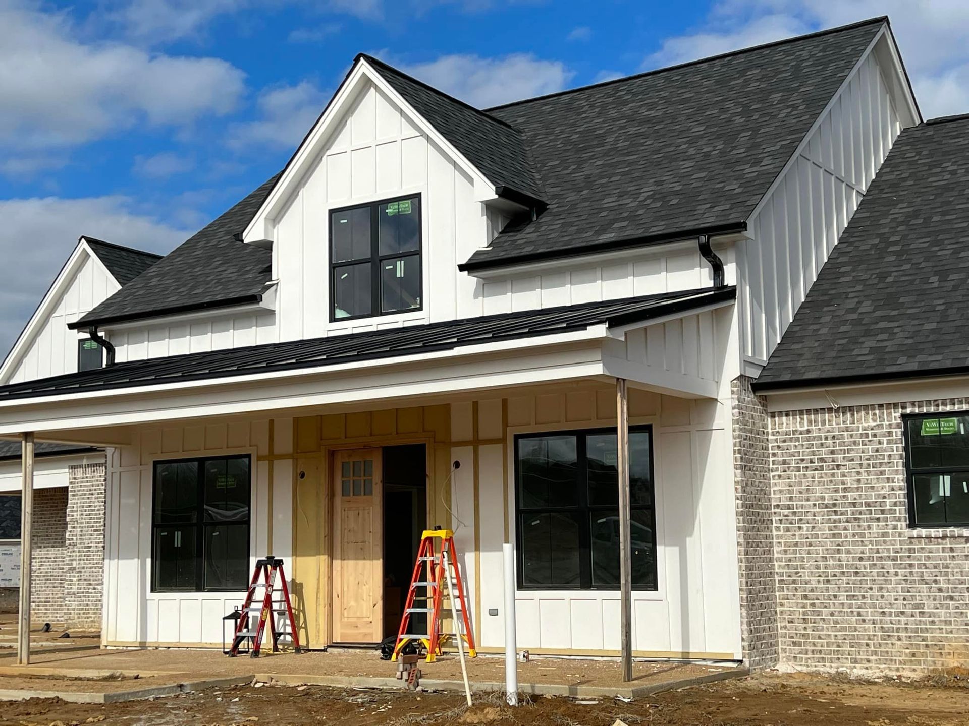 A large white house with a black roof is being built.
