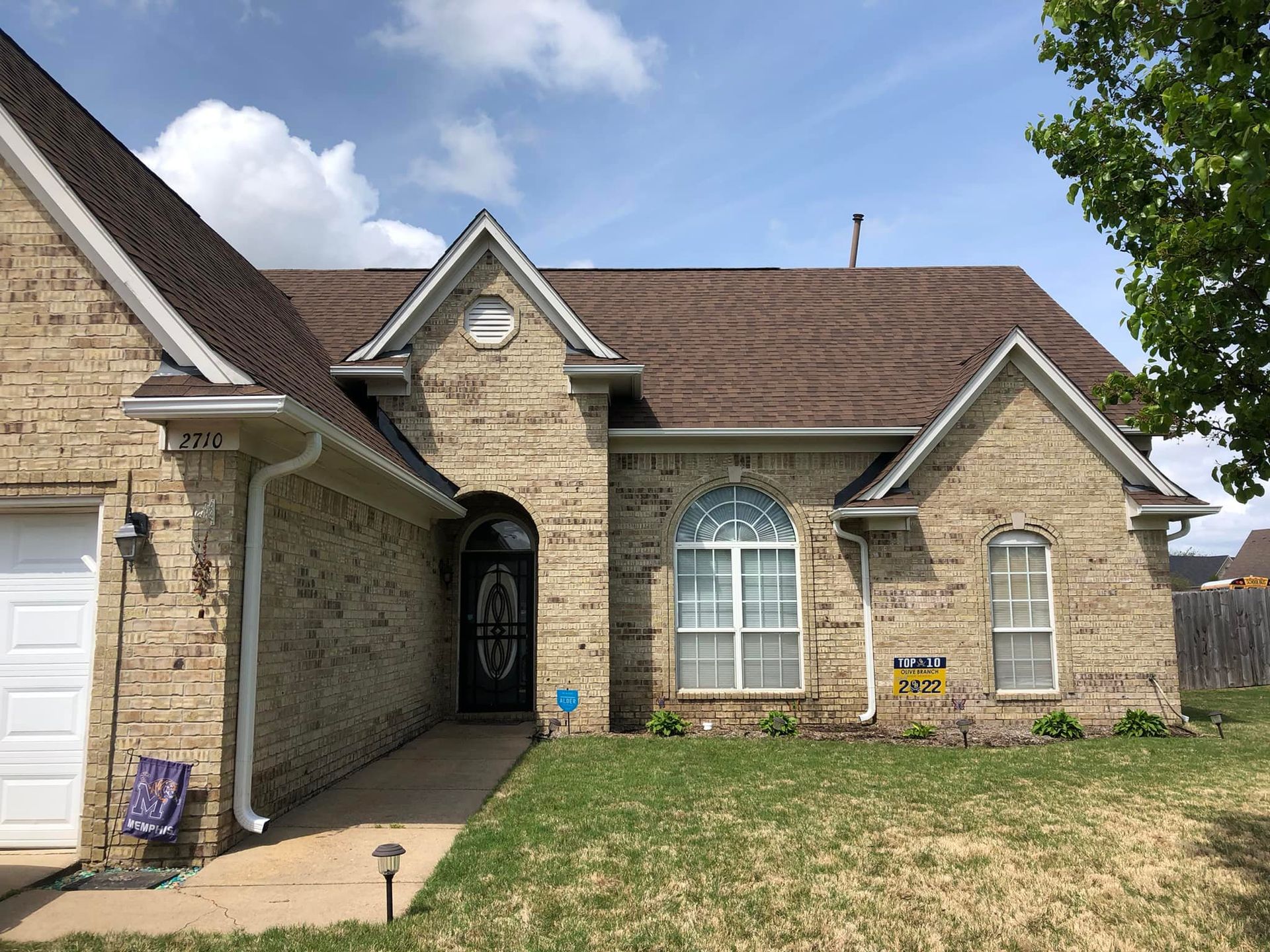 A brick house with a brown roof and a white garage door