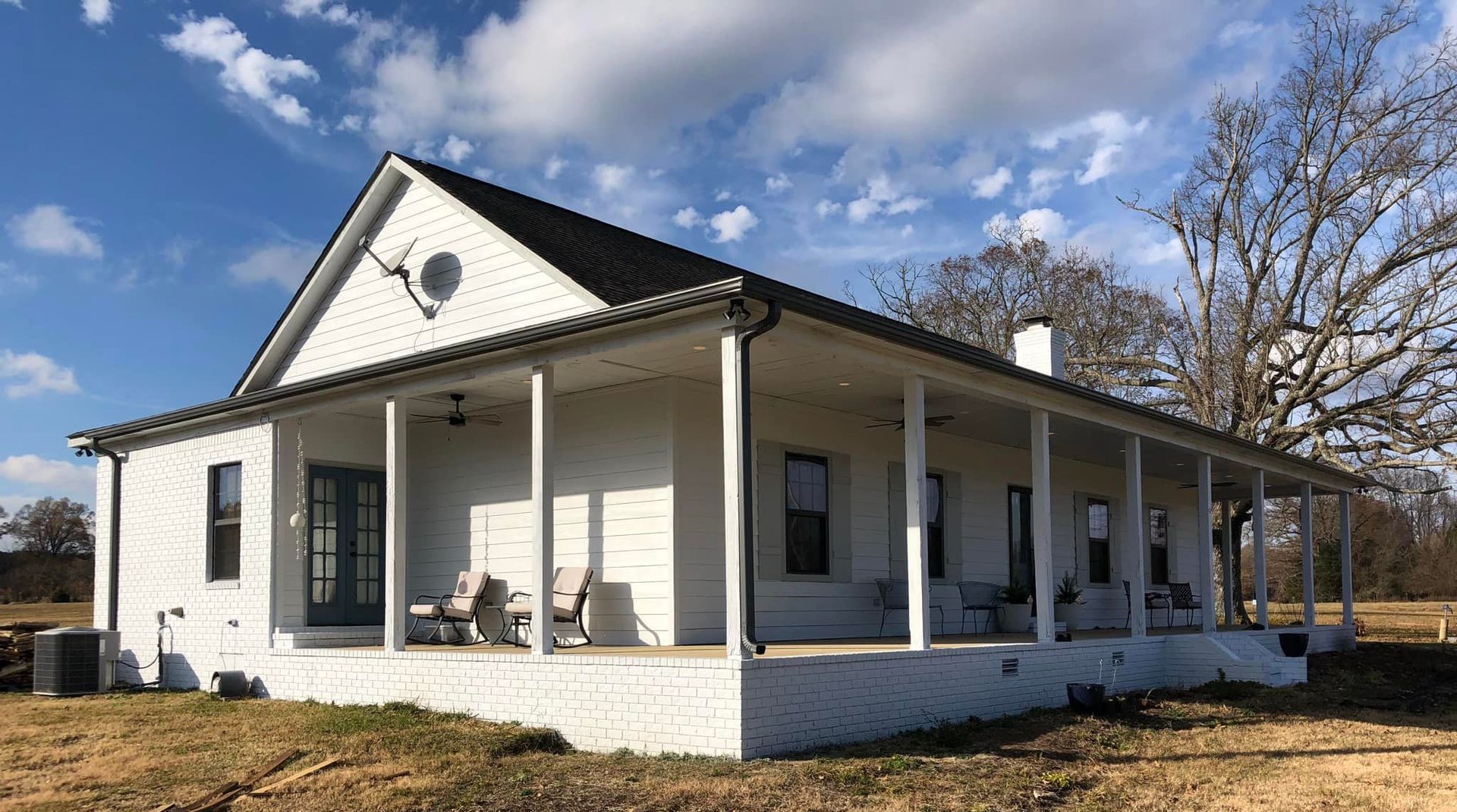 A white house with a porch and rocking chairs on it.