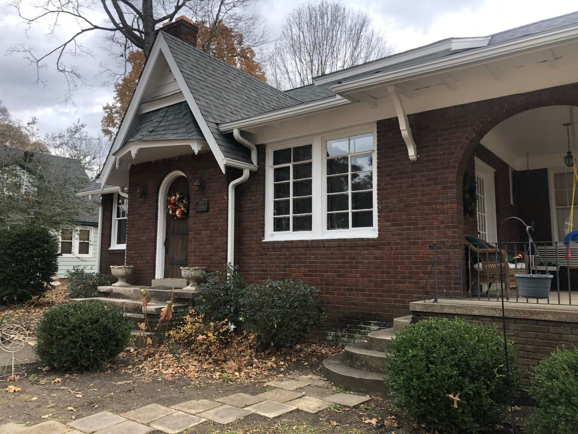 A brick house with a porch and stairs in front of it.