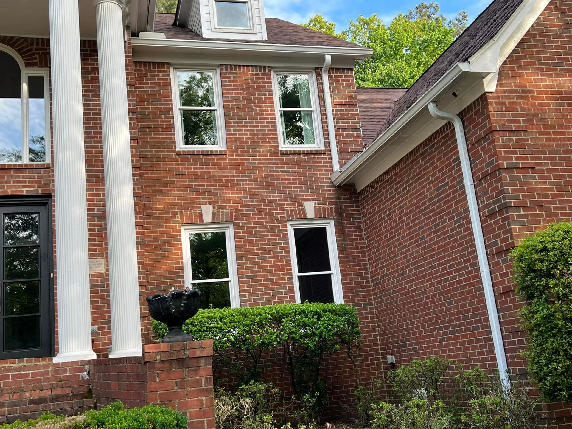 The front of a brick house with columns and windows.
