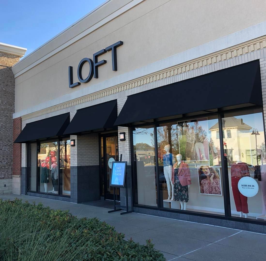 The outside of a loft store with black awnings