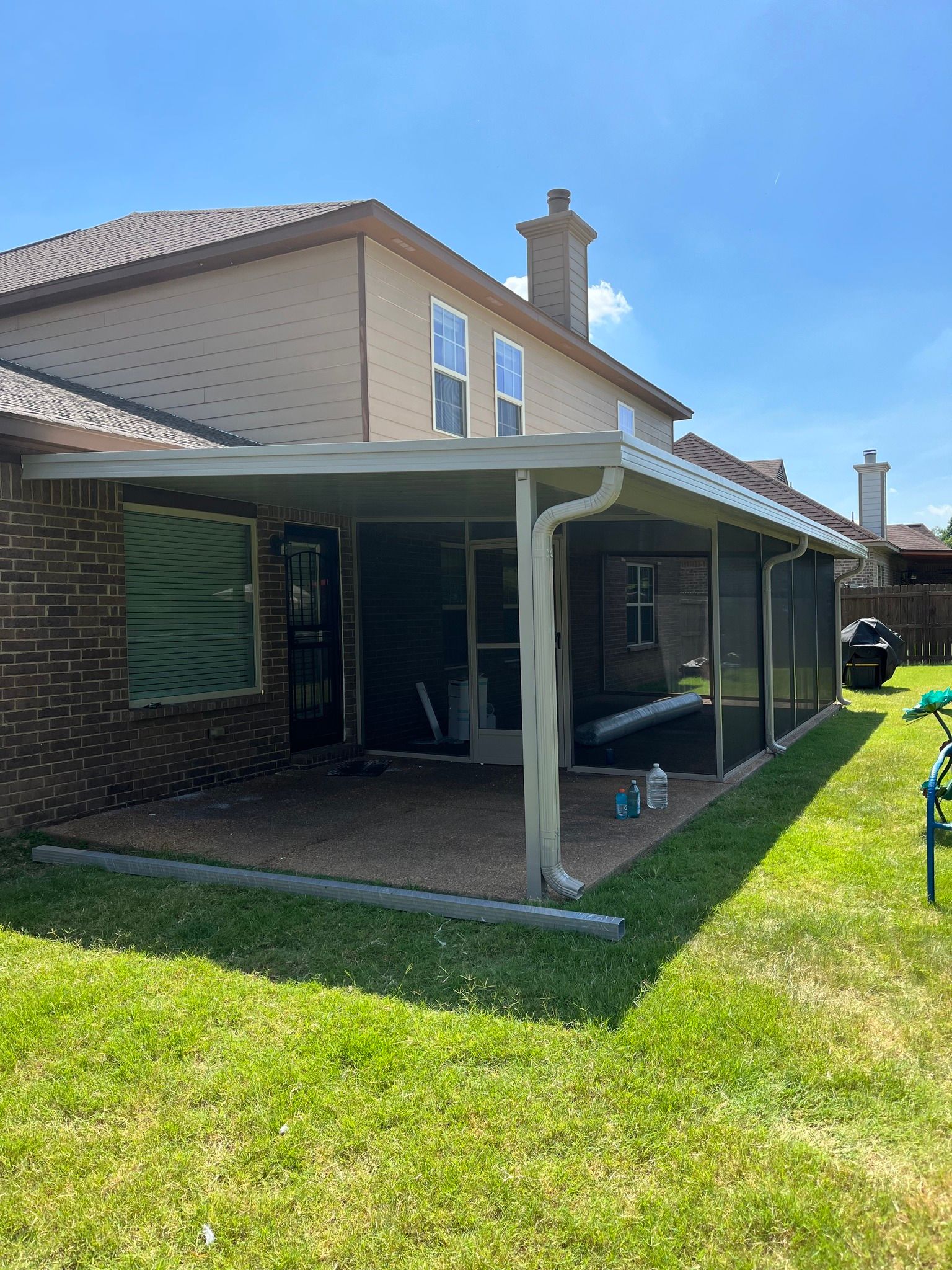 There is a covered patio in the backyard of a house.