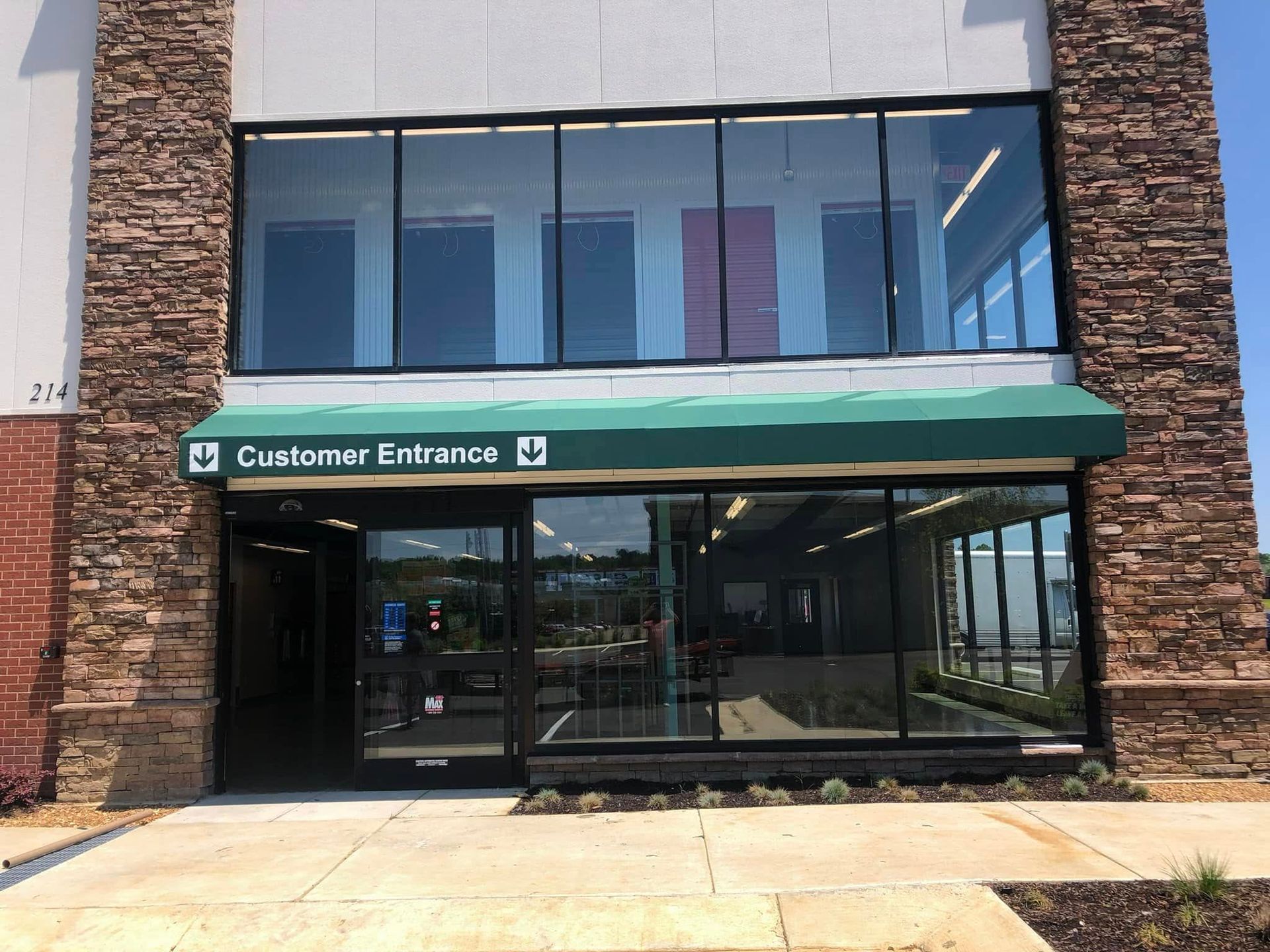A brick building with a green and white striped awning over the front door.