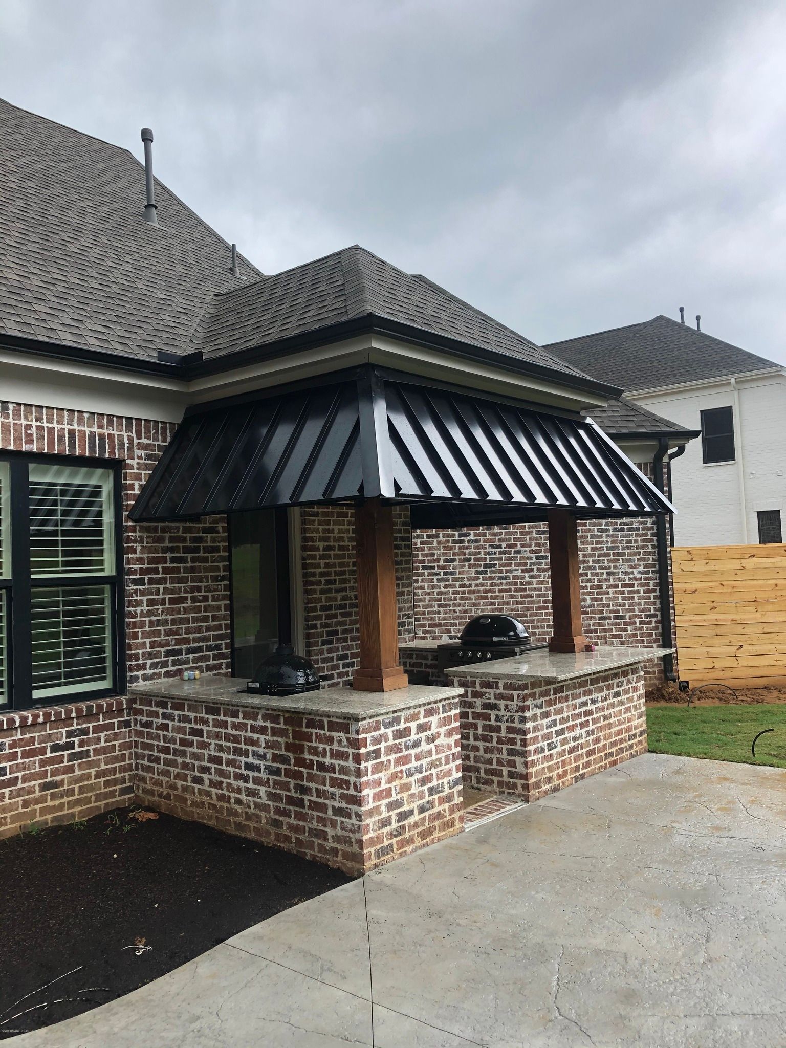 A brick house with a black awning on the side of it.
