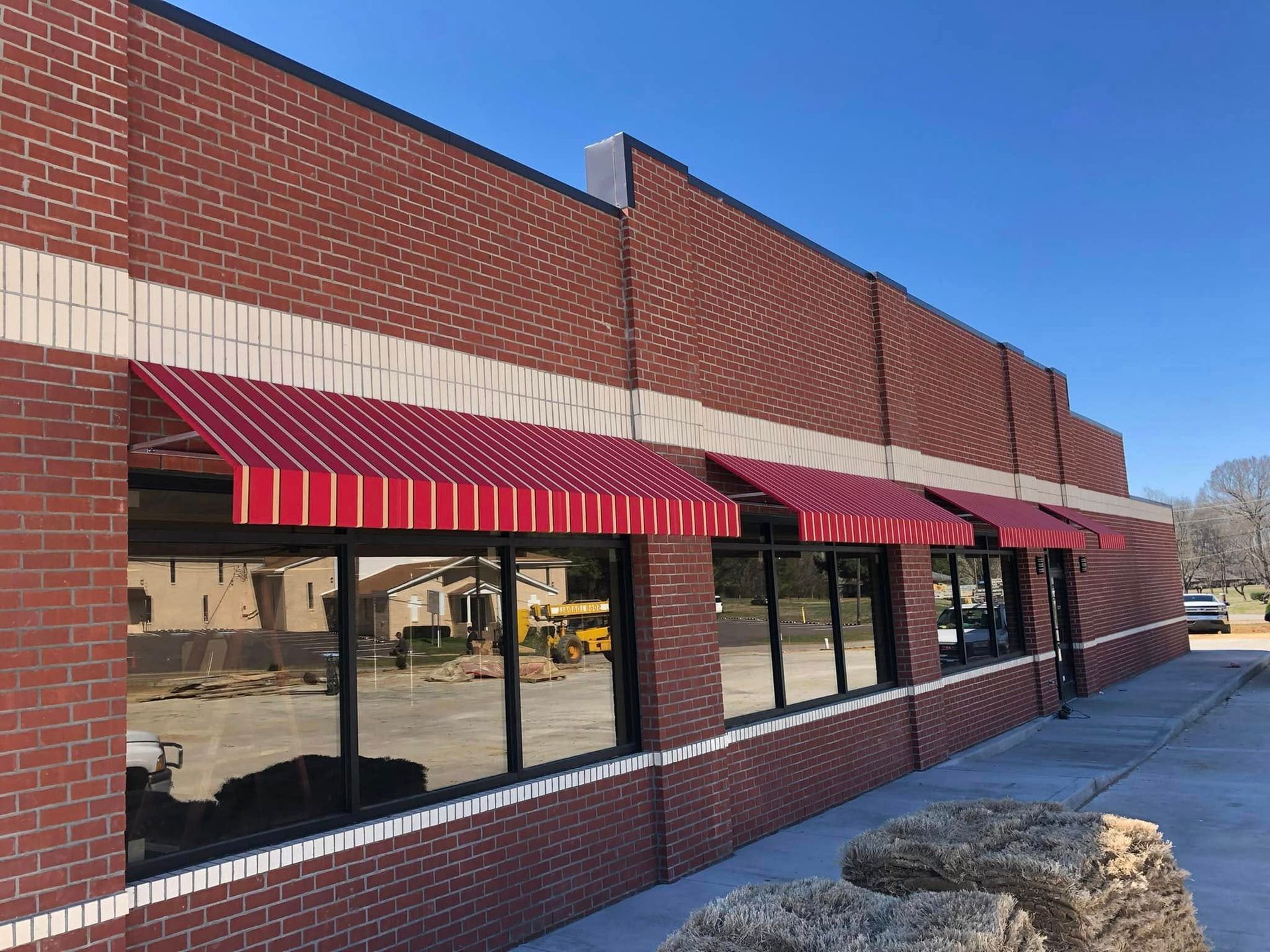 A red awning is on the side of a brick building.