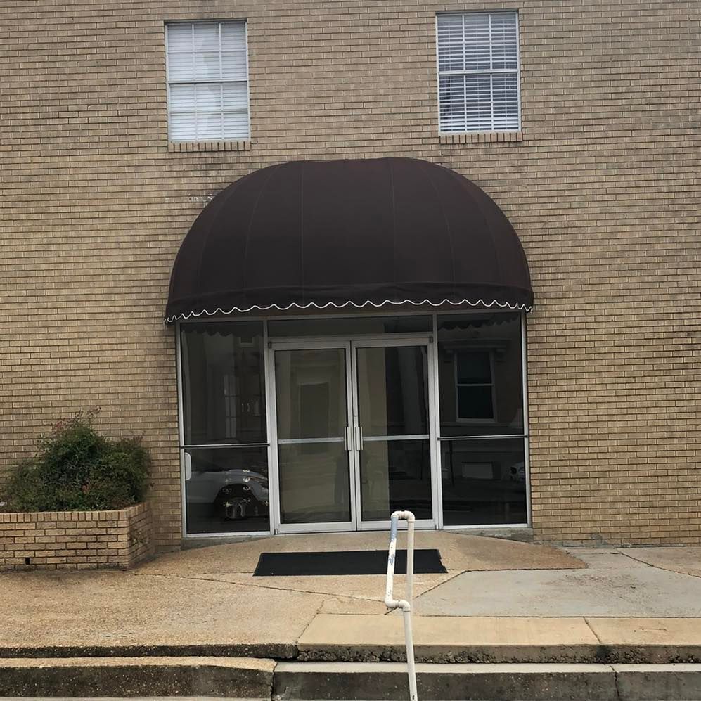 A brick building with a brown awning over the entrance