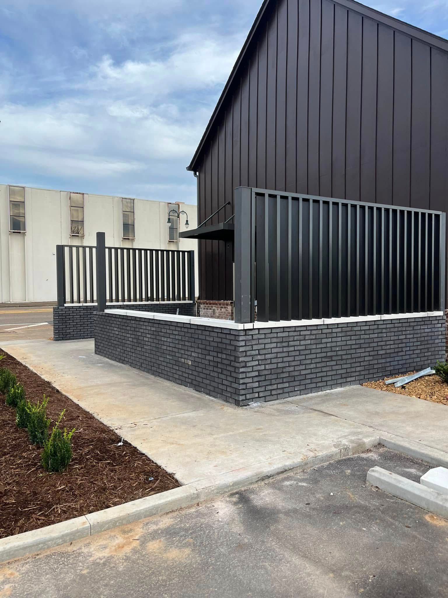 A building with a black fence and a brick wall in front of it.