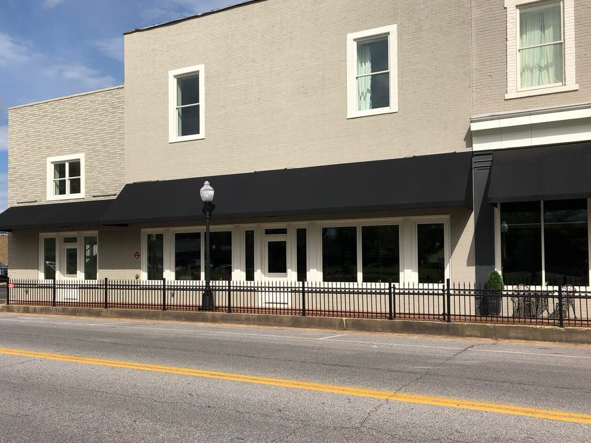 A large building with a black awning is sitting on the side of the road.