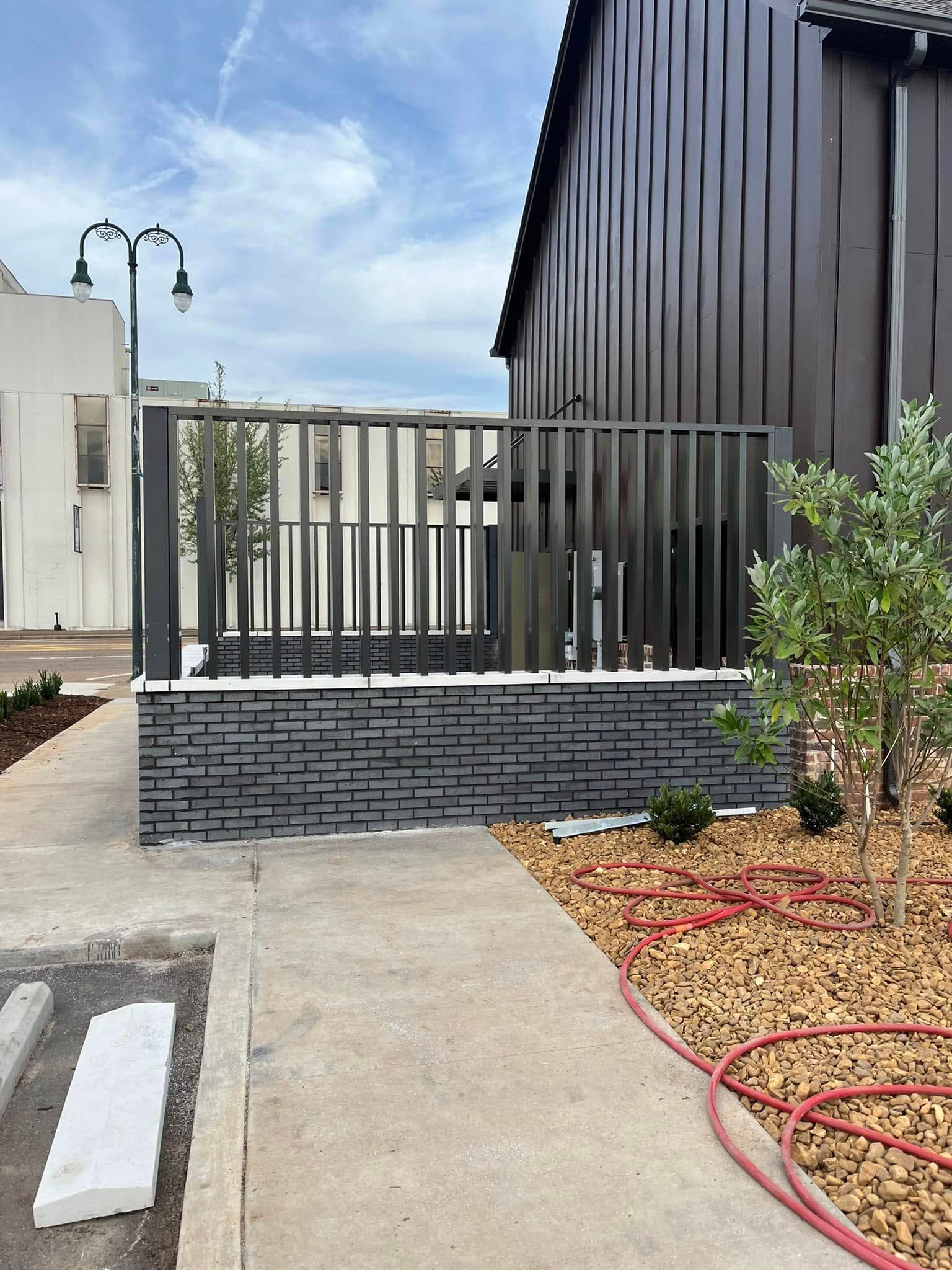 A fence is surrounding a sidewalk next to a building.