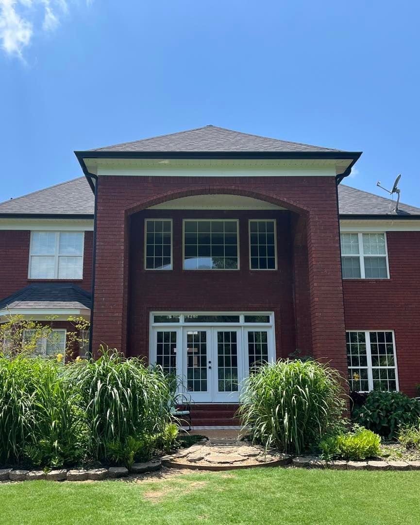A large red brick house with a lush green lawn in front of it.