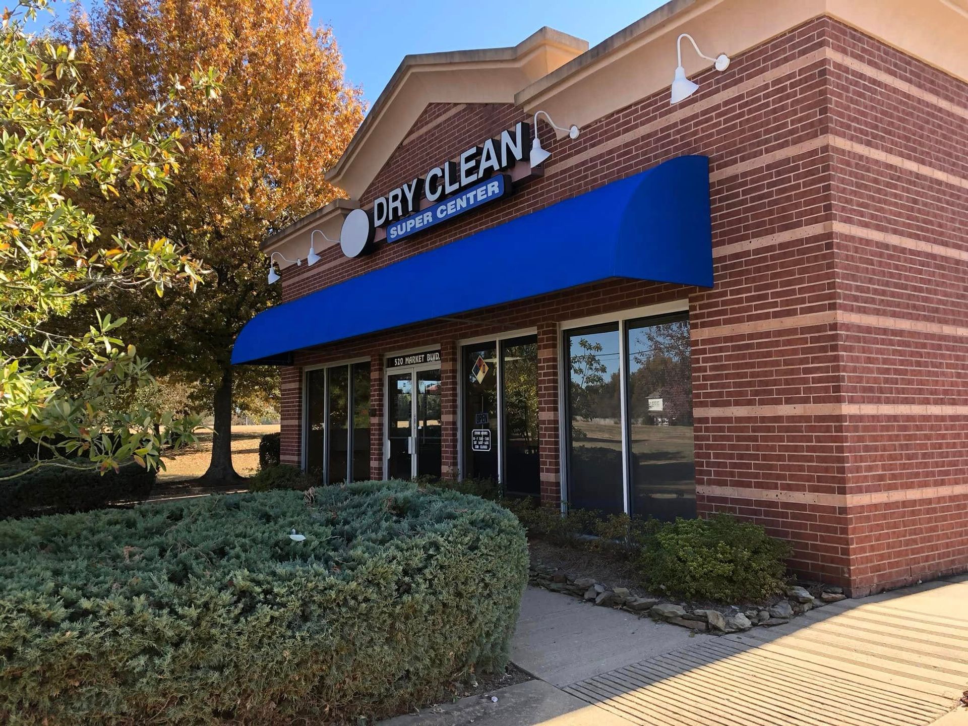 A brick building with a blue awning that says dry clean