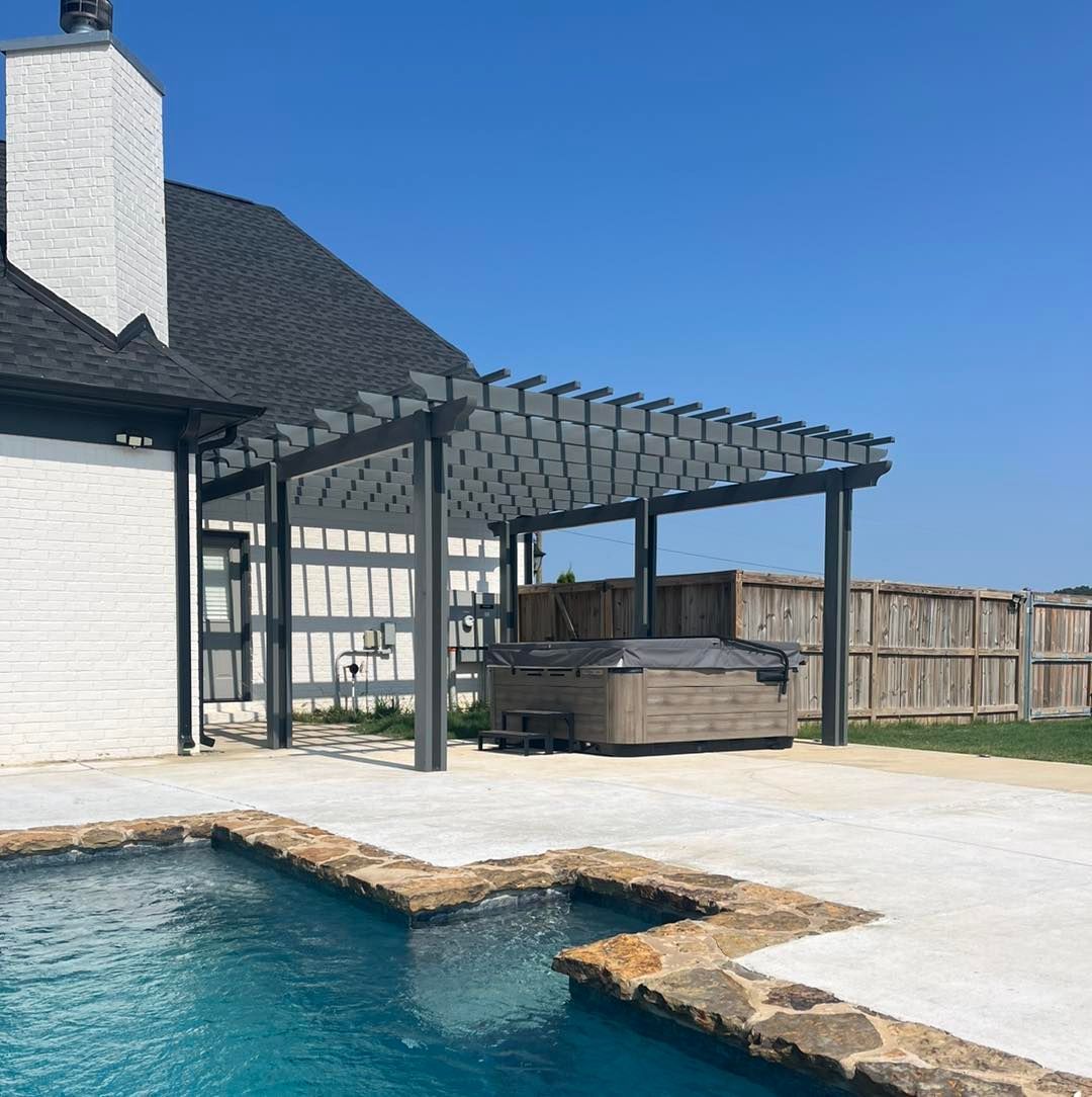 There is a swimming pool in front of a house with a pergola over it.