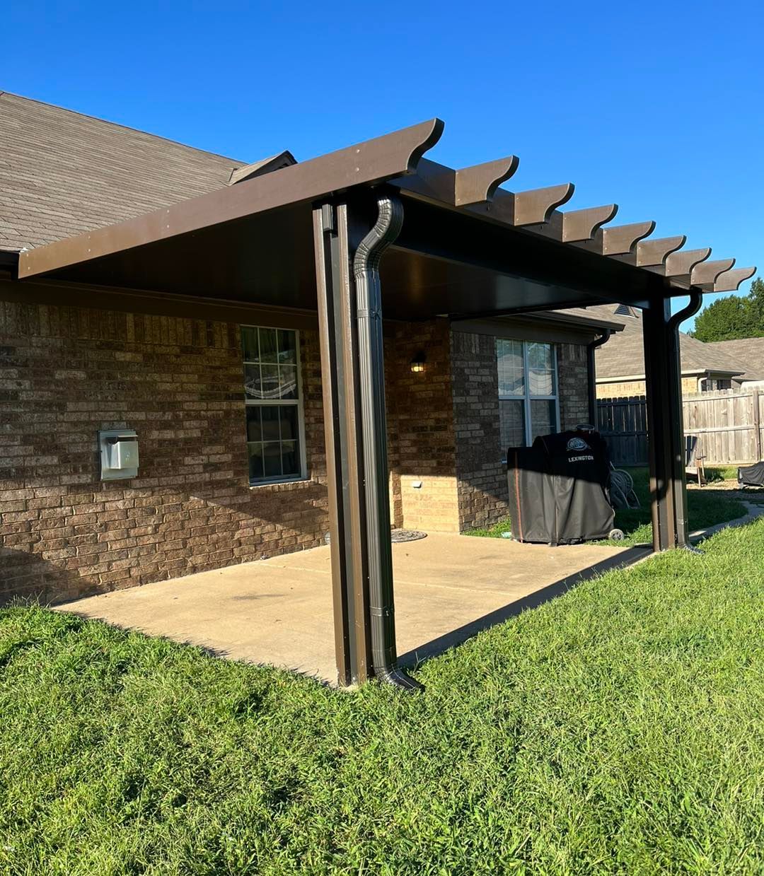 A pergola is sitting in the backyard of a house.