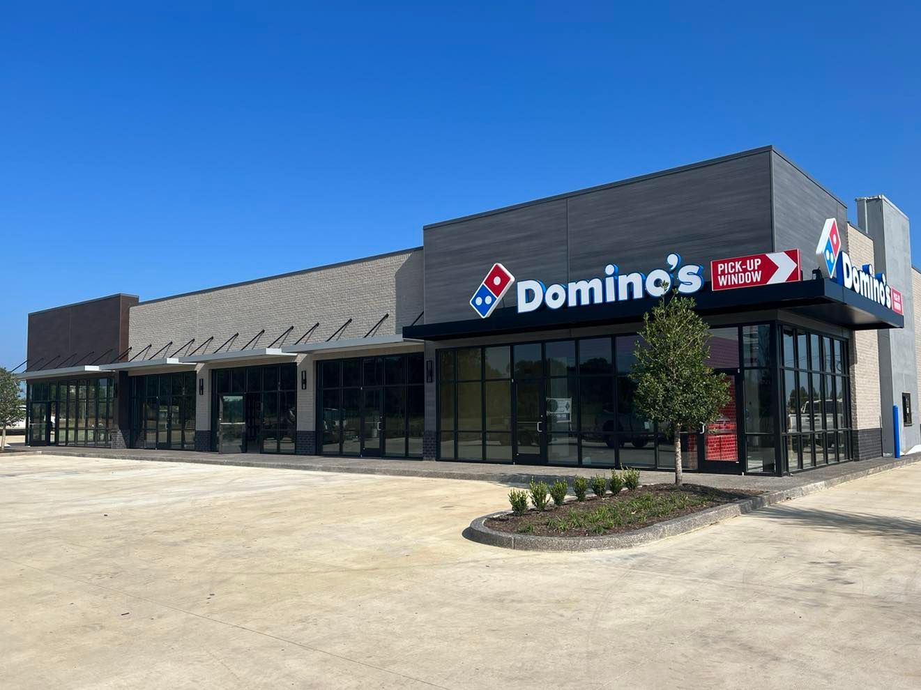The outside of a domino 's pizza restaurant with a lot of windows.