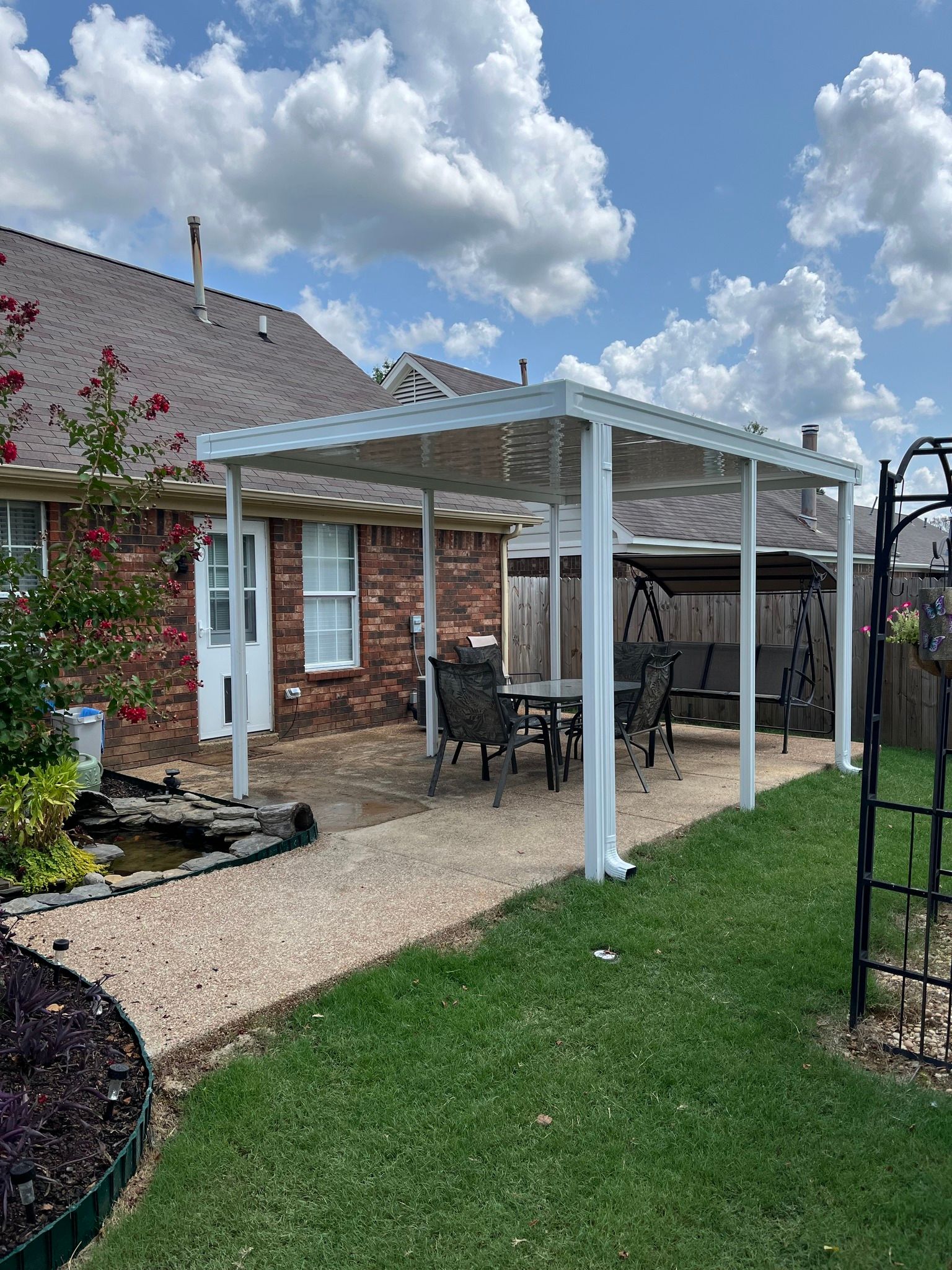 There is a pergola in the backyard of a house.