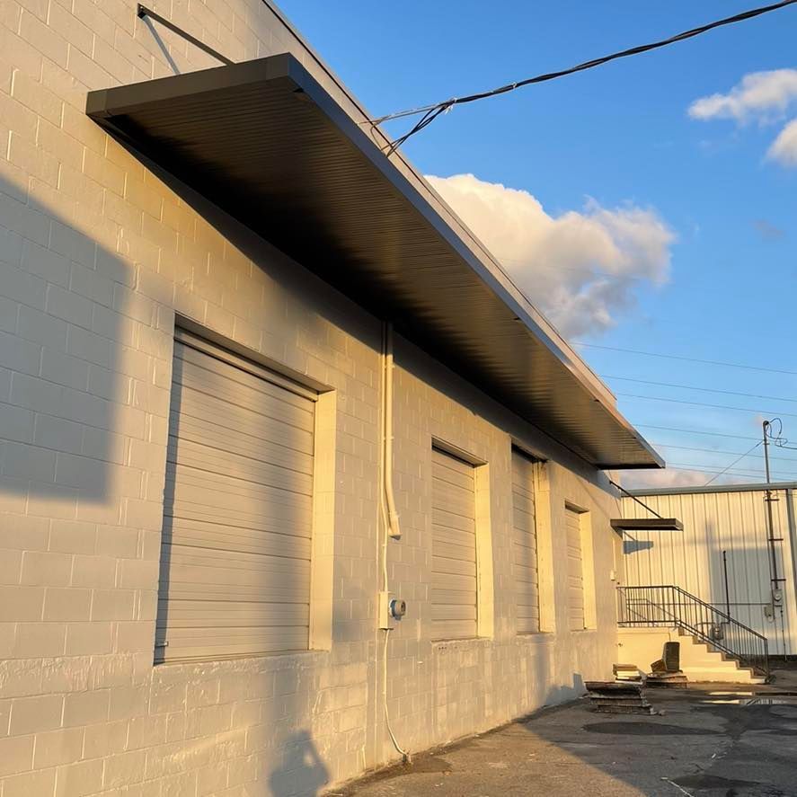 A white building with a black awning on the side