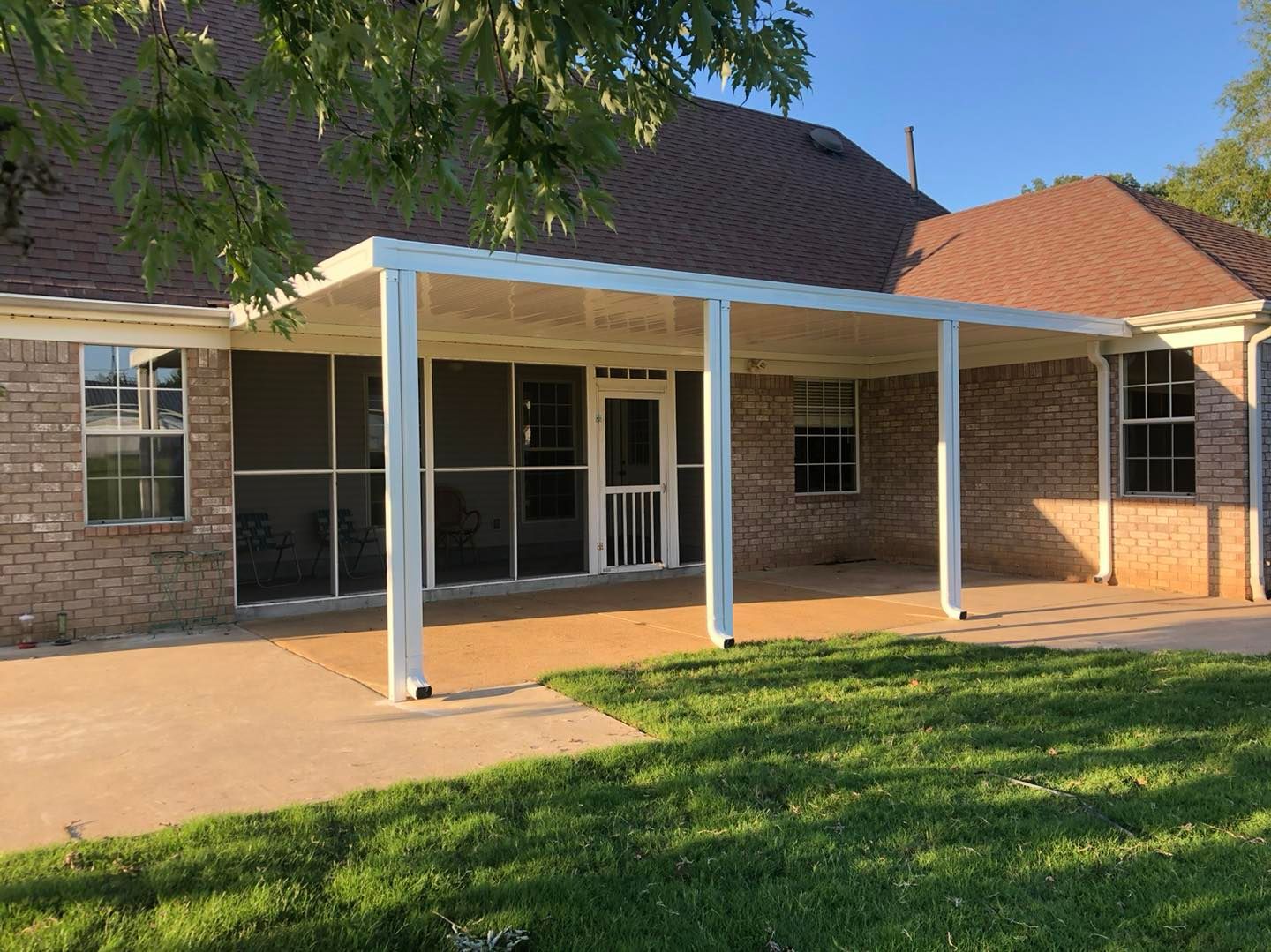 A brick house with a screened in porch and a covered patio.