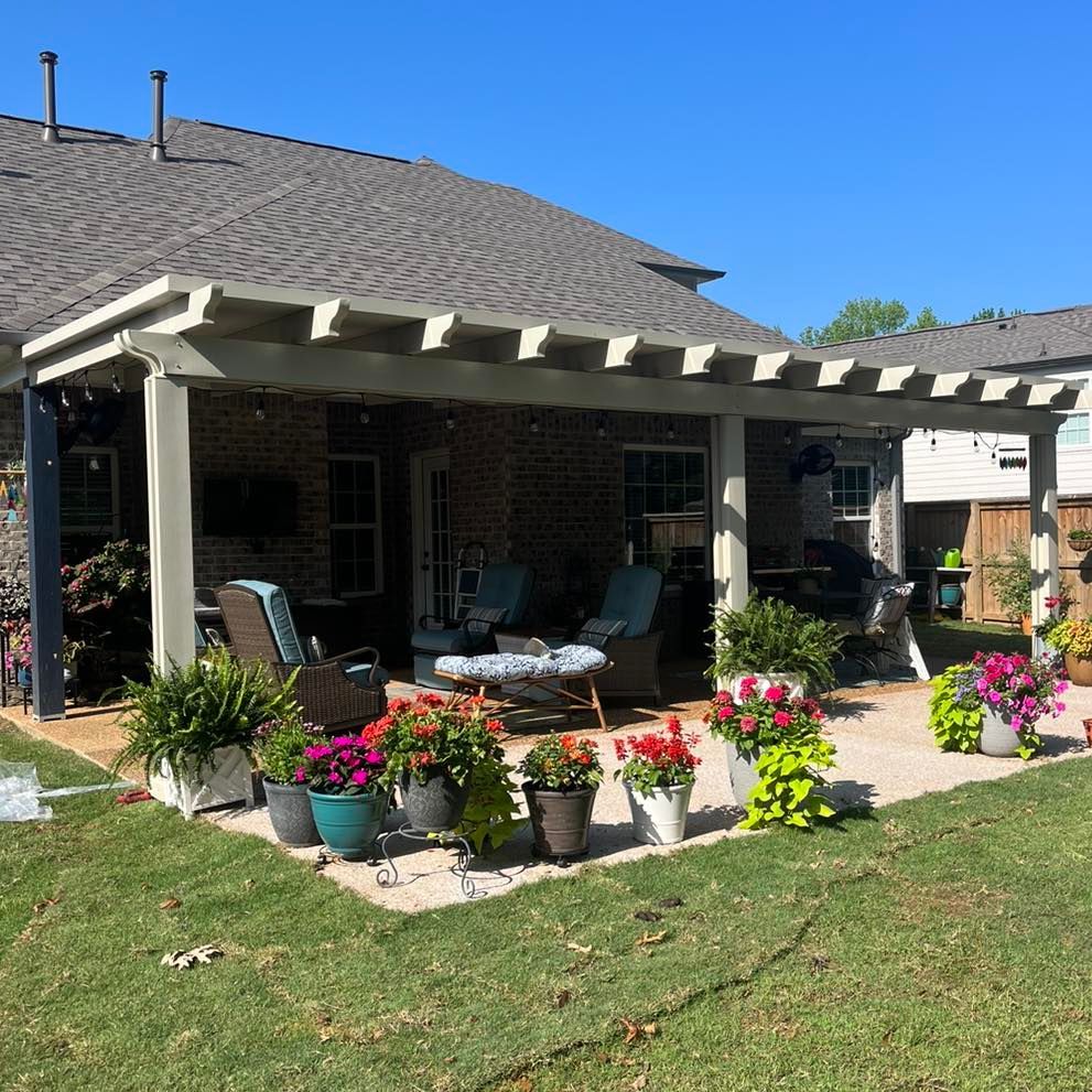 A patio with a pergola and flowers in front of a house