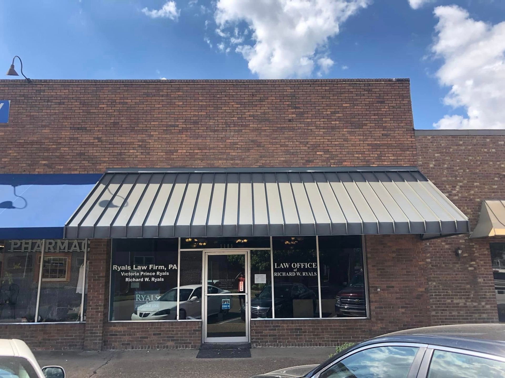 A brick building with a white awning and a car parked in front of it
