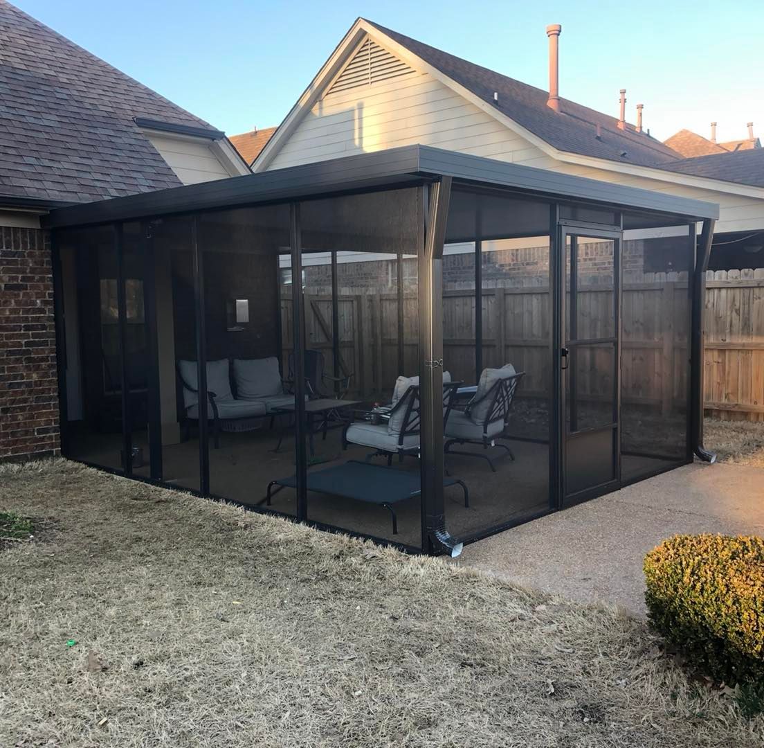 A screened in porch with chairs and a table in front of a house.