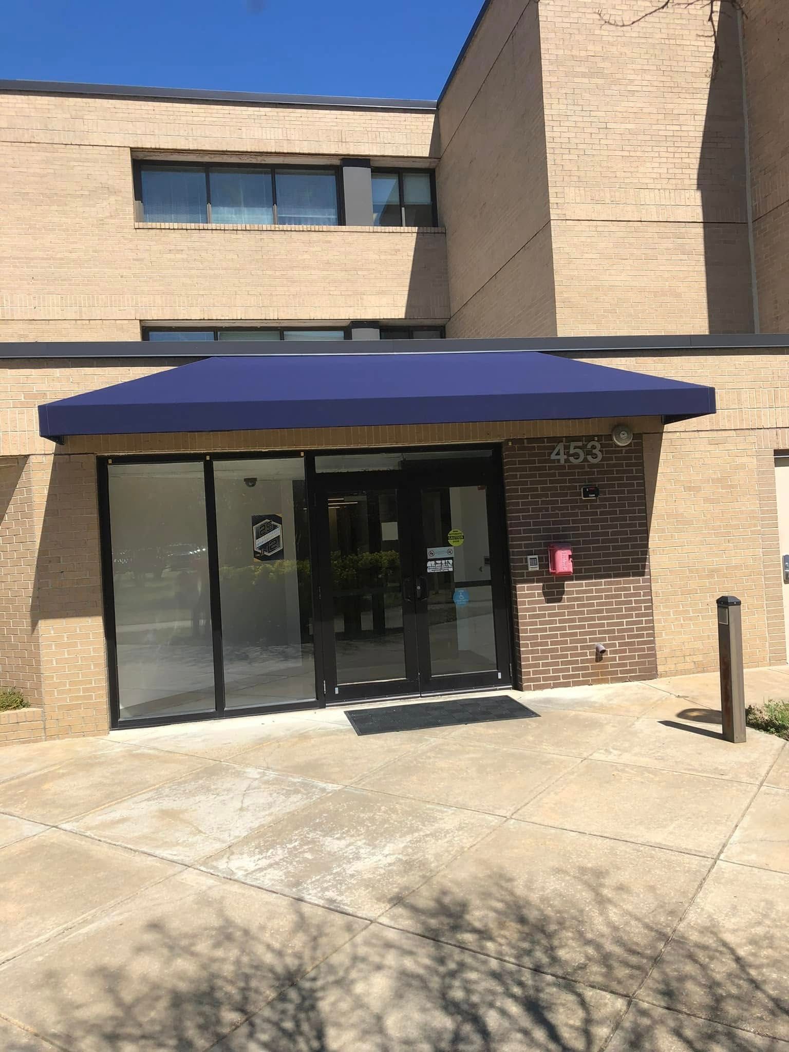 A brick building with a blue awning over the entrance