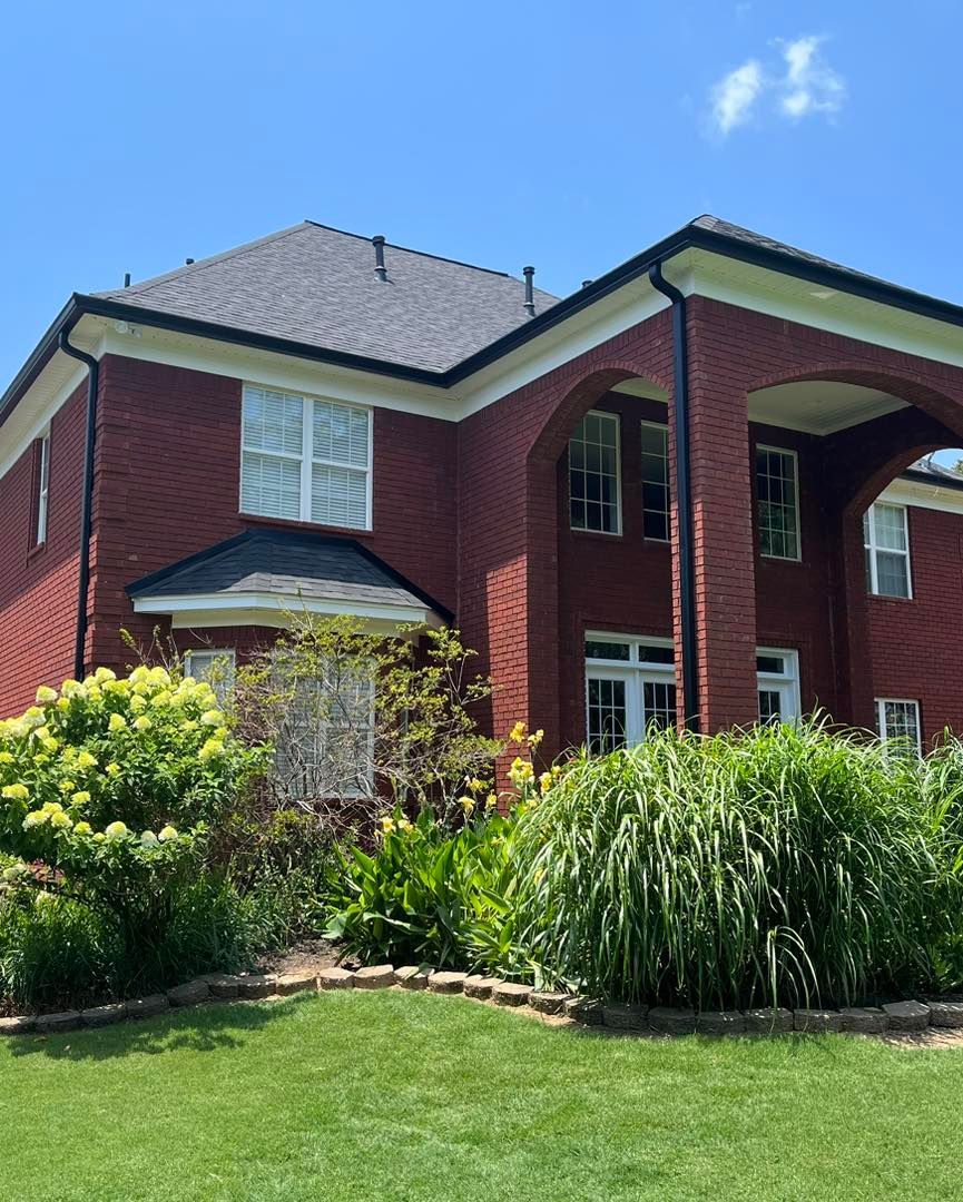 A large red brick house with a lush green lawn in front of it.