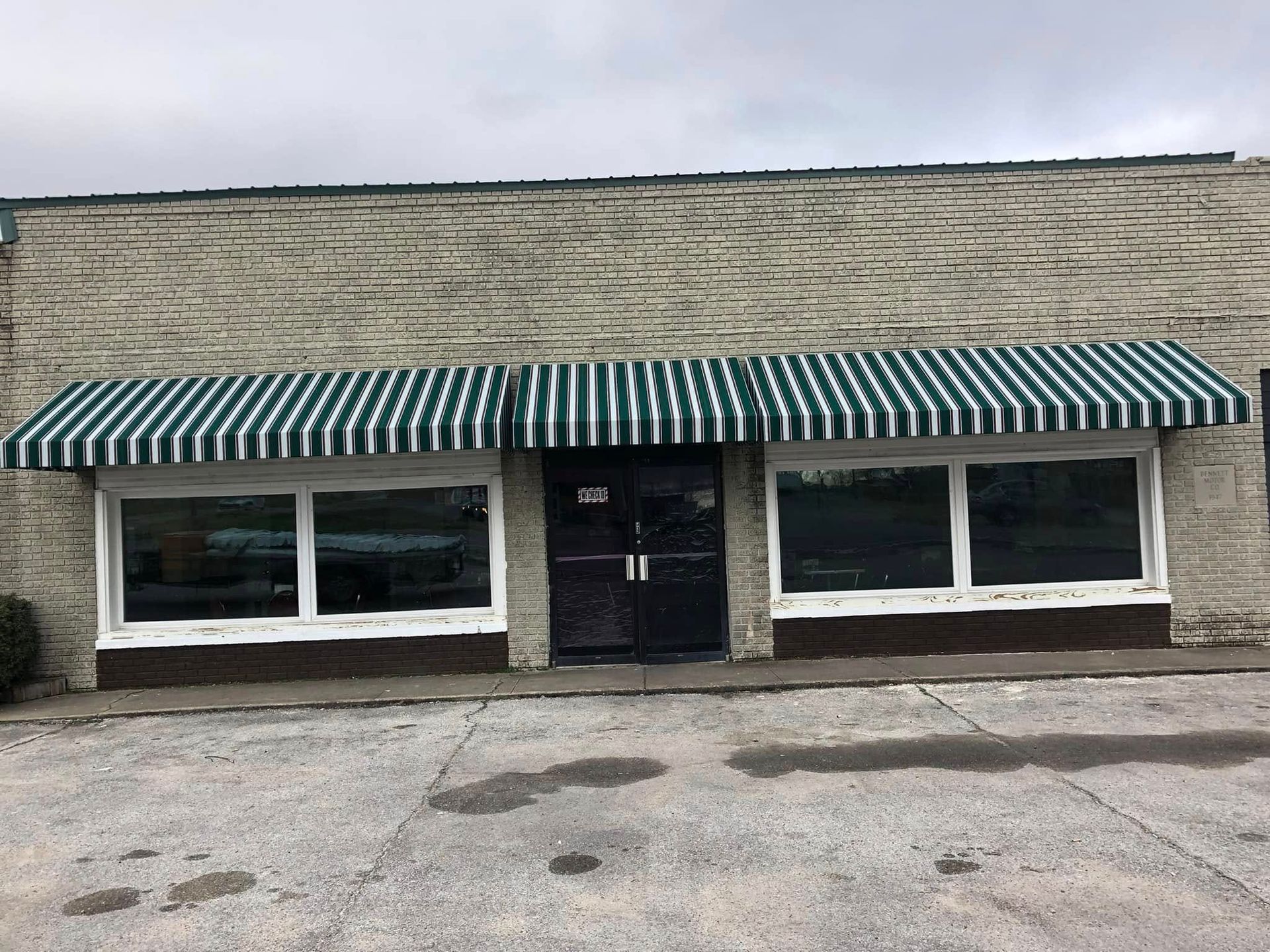 A brick building with a green and white striped awning over the front door.