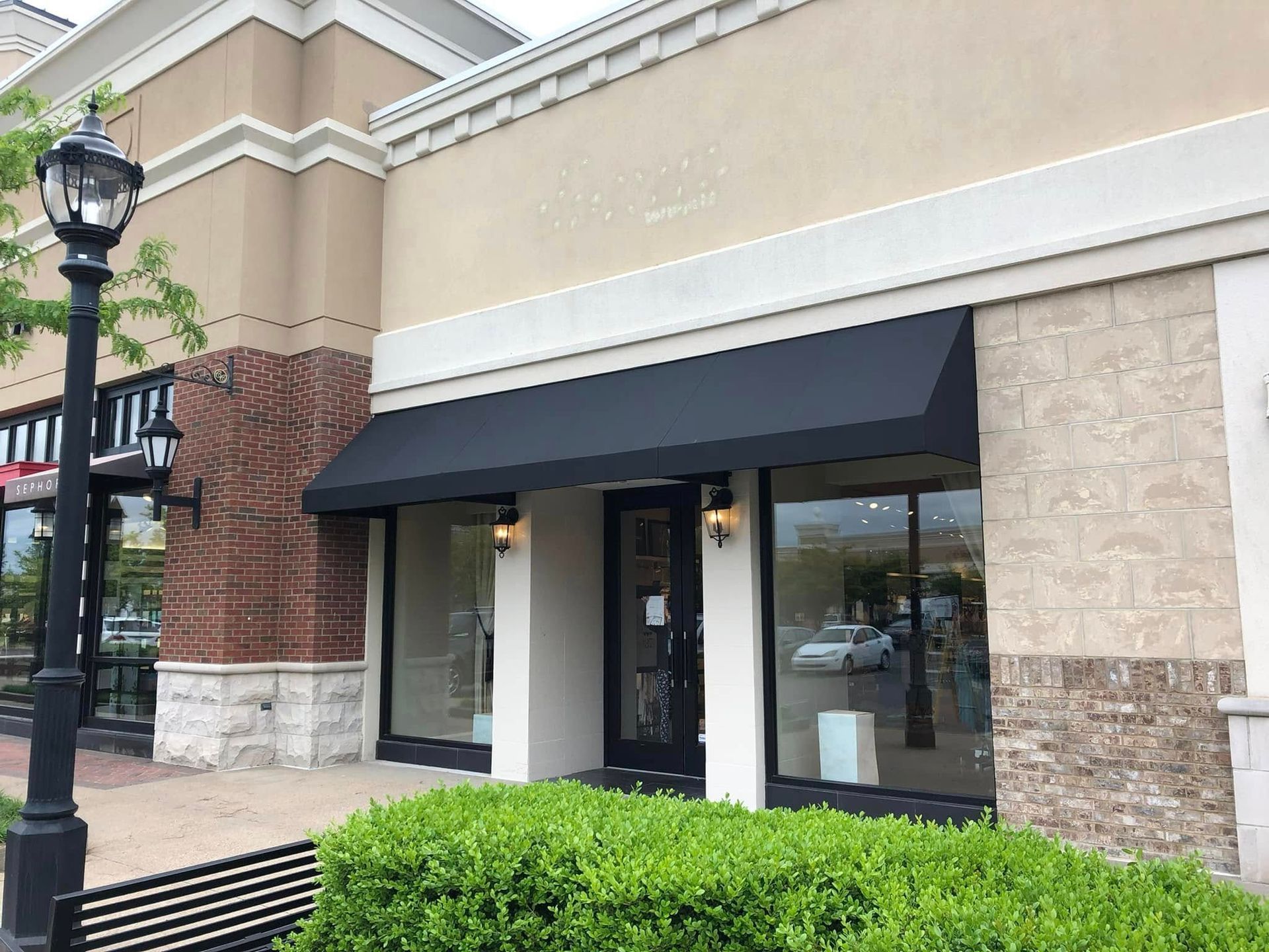 A store front with a black awning over the door.