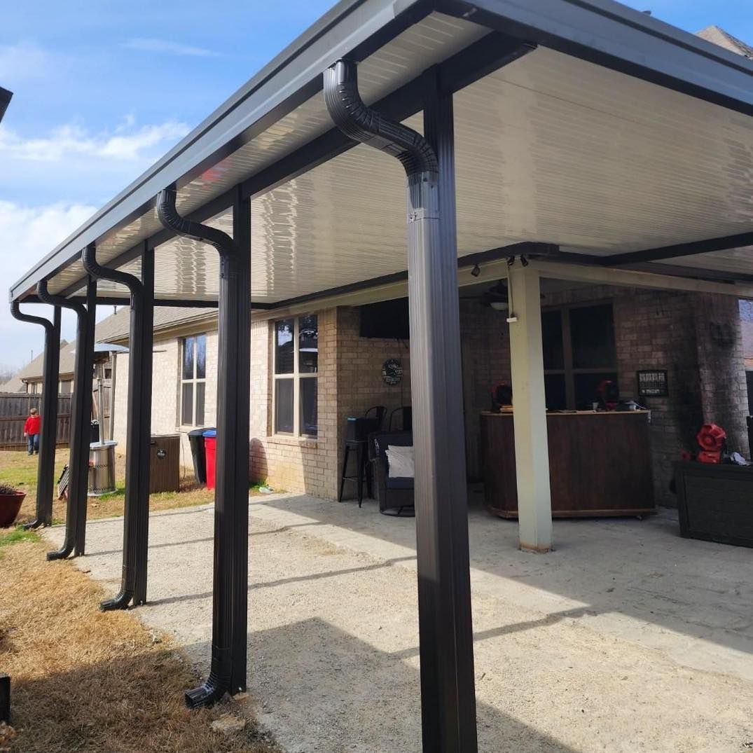 A covered patio with a brick building in the background