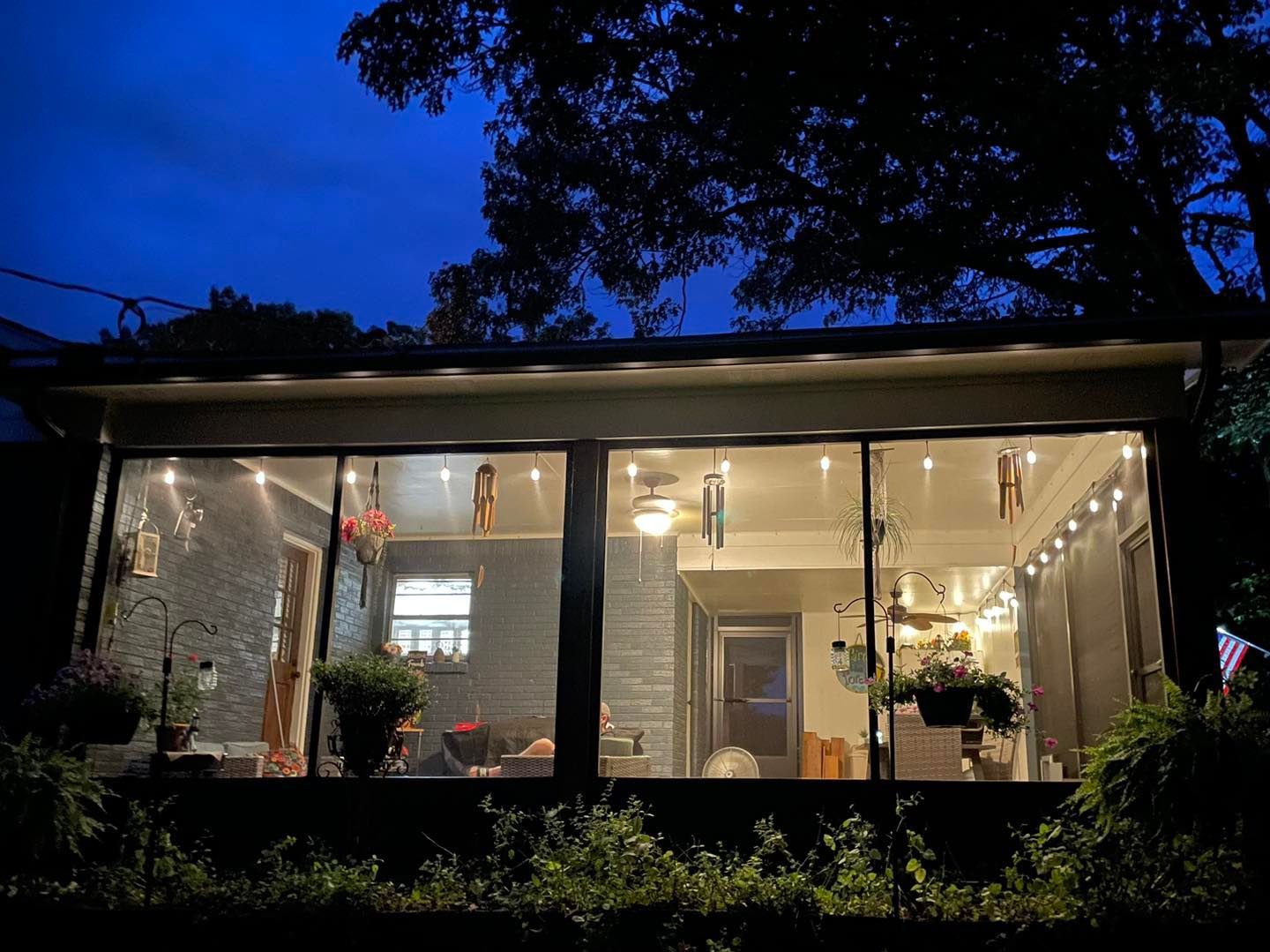 A house with a lot of windows is lit up at night.