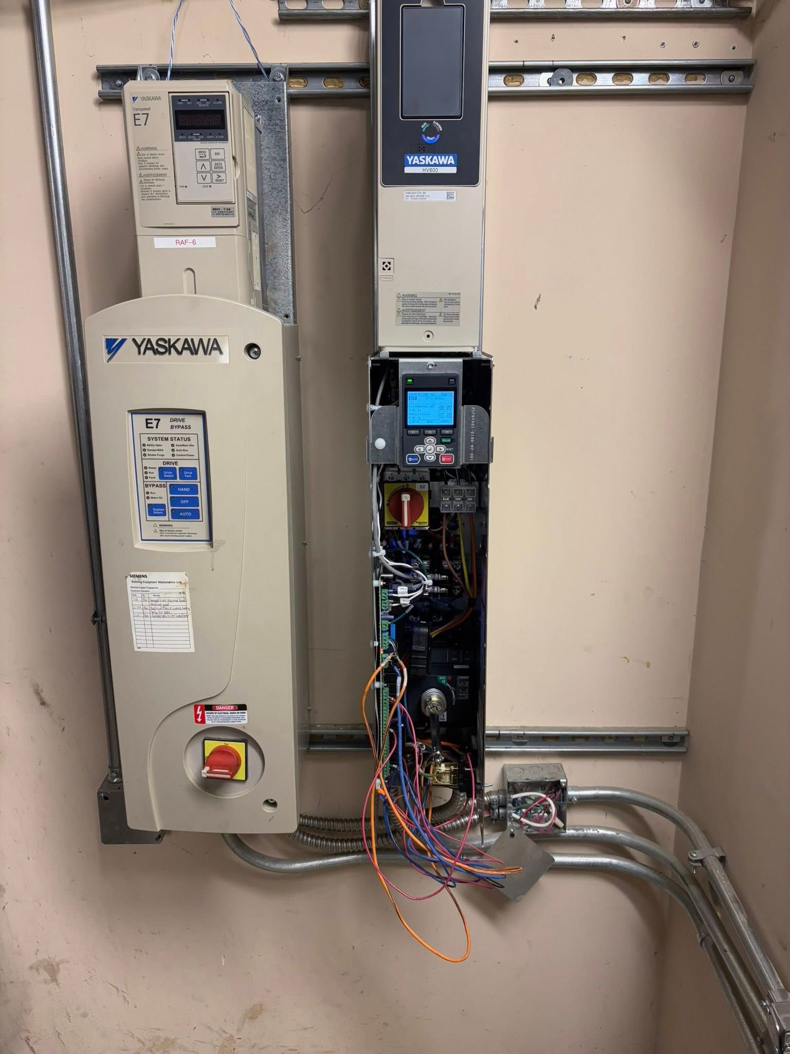 Two beige industrial electrical control panels mounted on a wall with exposed wiring and conduits.