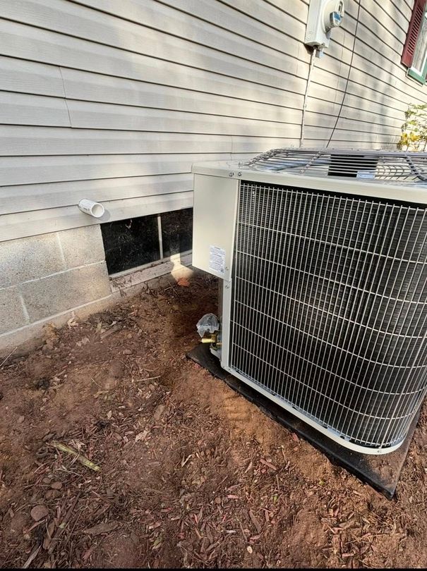 AC unit next to a house with a basement window and exposed dirt ground.