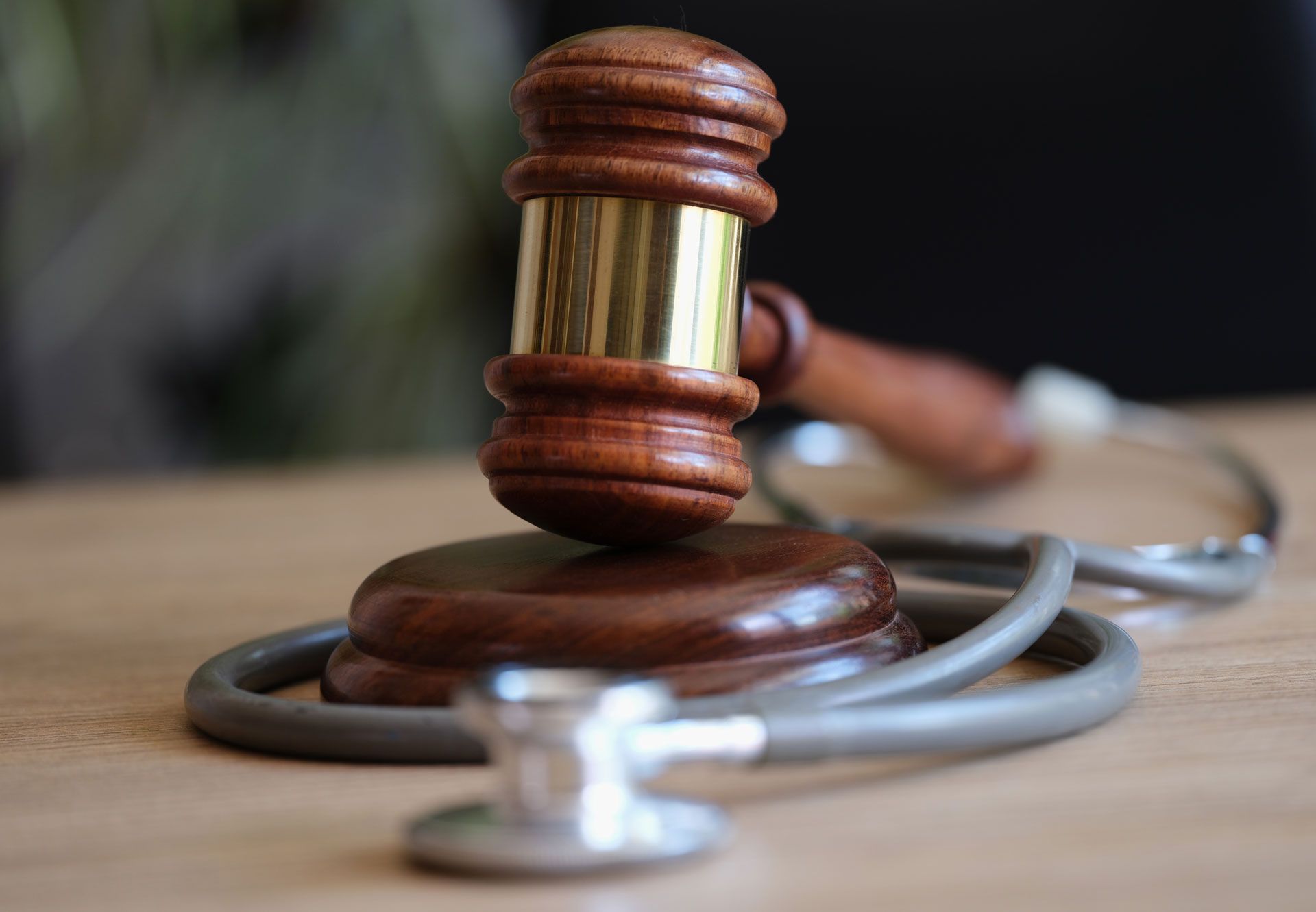 A wooden judge 's gavel is sitting on top of a wooden table next to a stethoscope