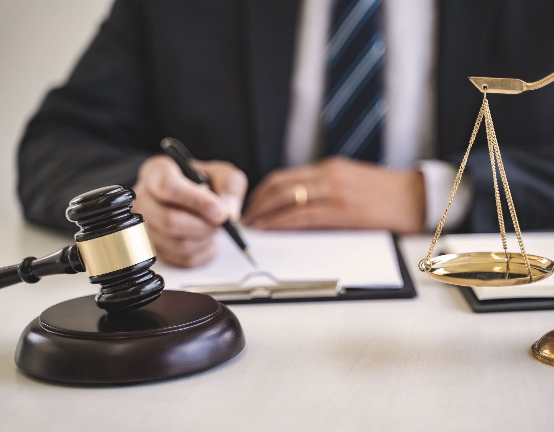 A judge is writing on a clipboard next to a gavel and scales of justice
