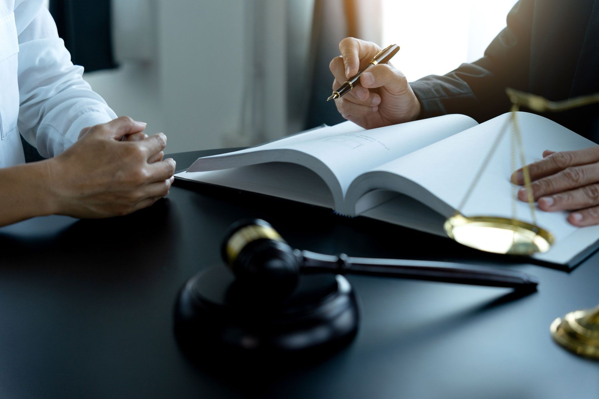 Two people are sitting at a table with a book and a gavel