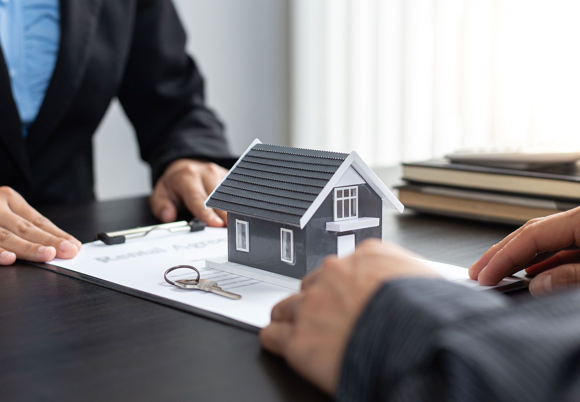 A man and a woman are sitting at a table with a model house and keys