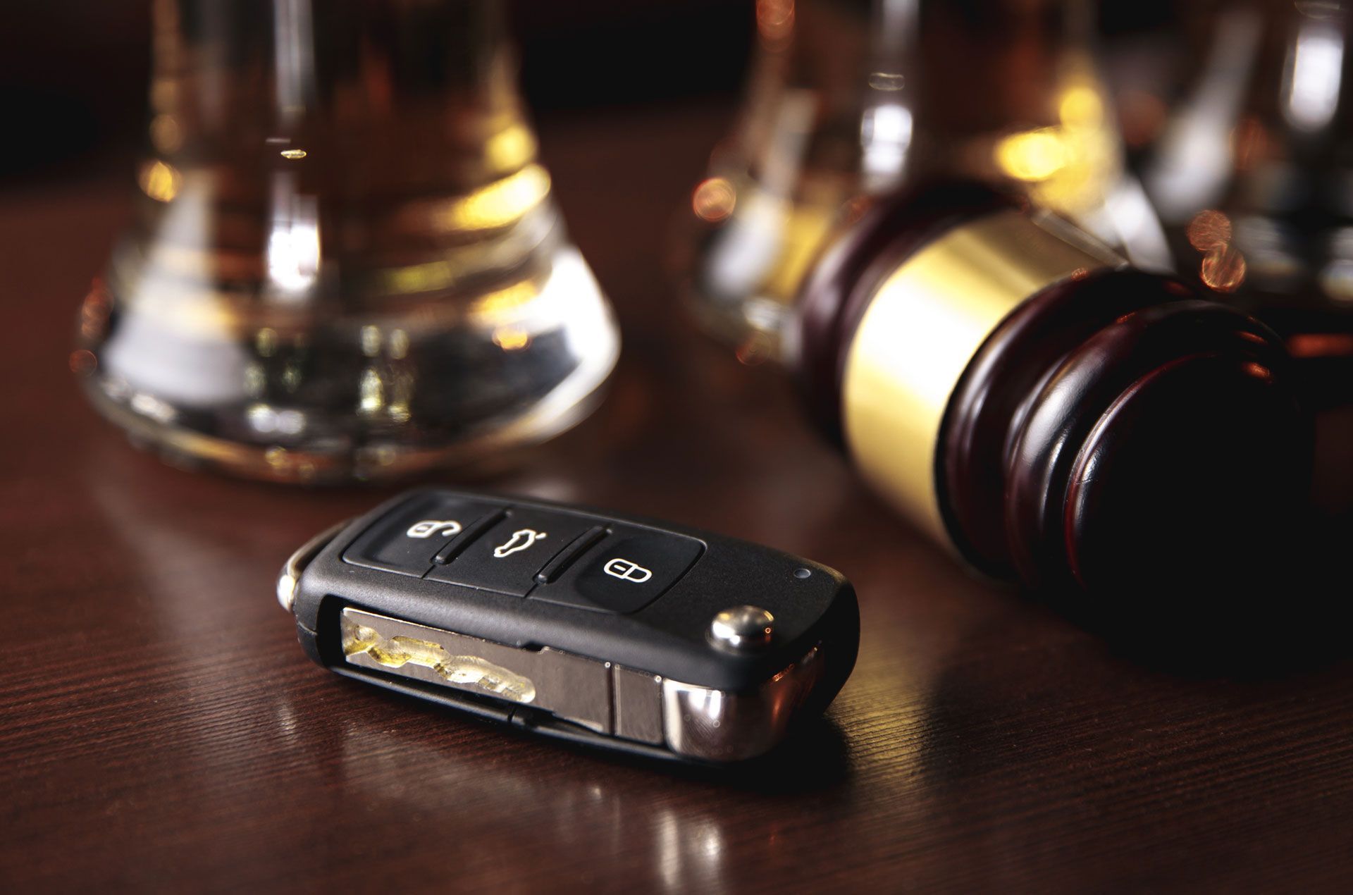 A car key is sitting on a table next to a judge 's gavel and a glass of beer